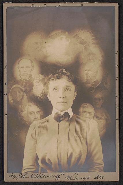 Augmented photograph of a young man with short, curly hair, dressed in a vintage suit with a bow tie. Surrounding him are faint, ghost-like images of various older men and women, creating a surreal, layered portrait effect.