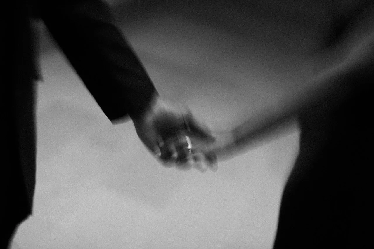 Close-up of two hands holding each other in black-and-white
