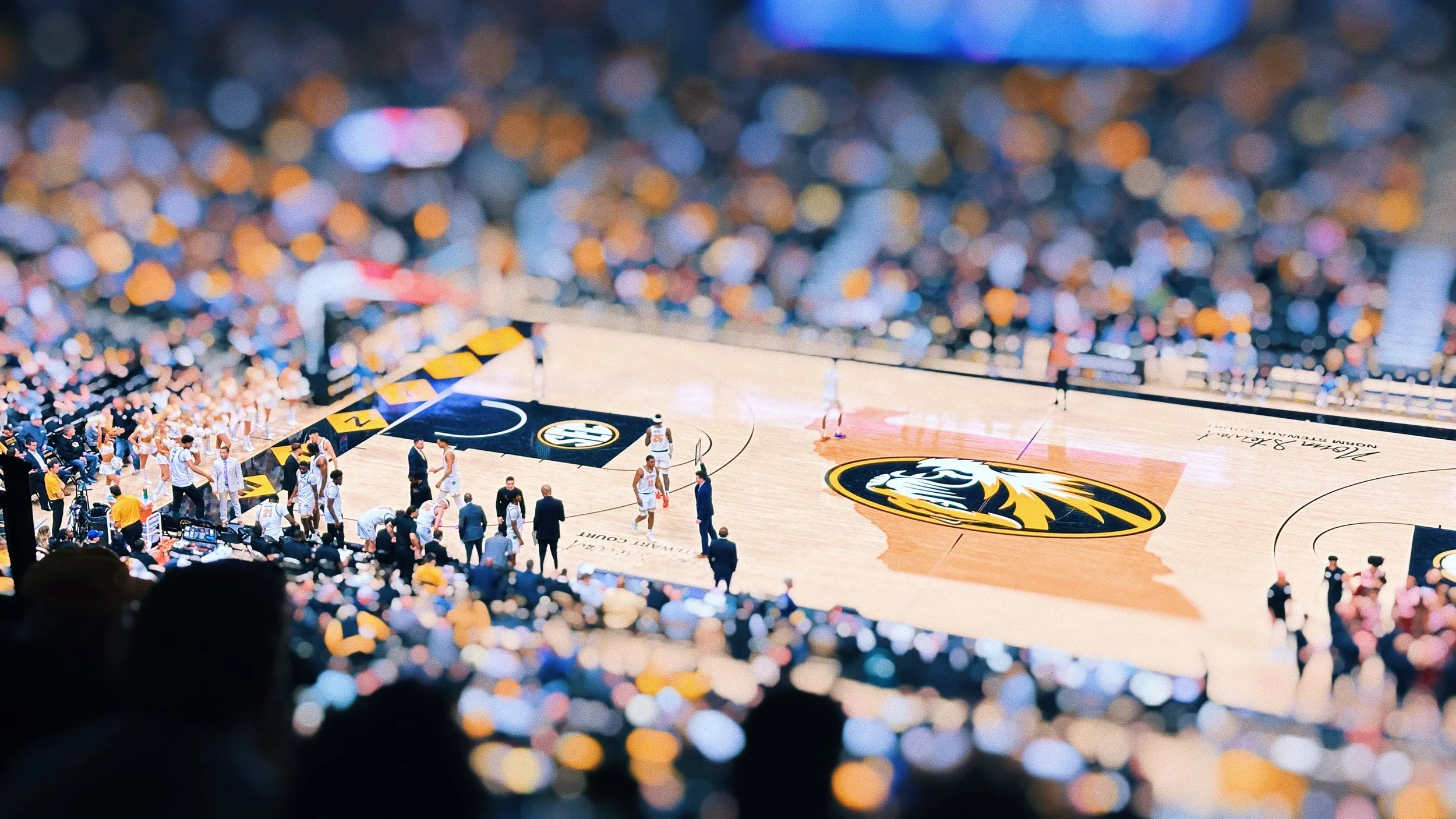 Basketball court with players and referees, surrounded by a crowd in a stadium, featuring the logo of the Atlanta Hawks.