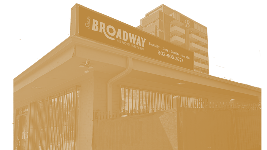 The Broadway headquarters building features a large sign with contact number 303-905-2827 and mentions services like hospitality, safety, and sanitation. The building is multi-story, with a brick exterior, and is fenced with vertical iron bars.