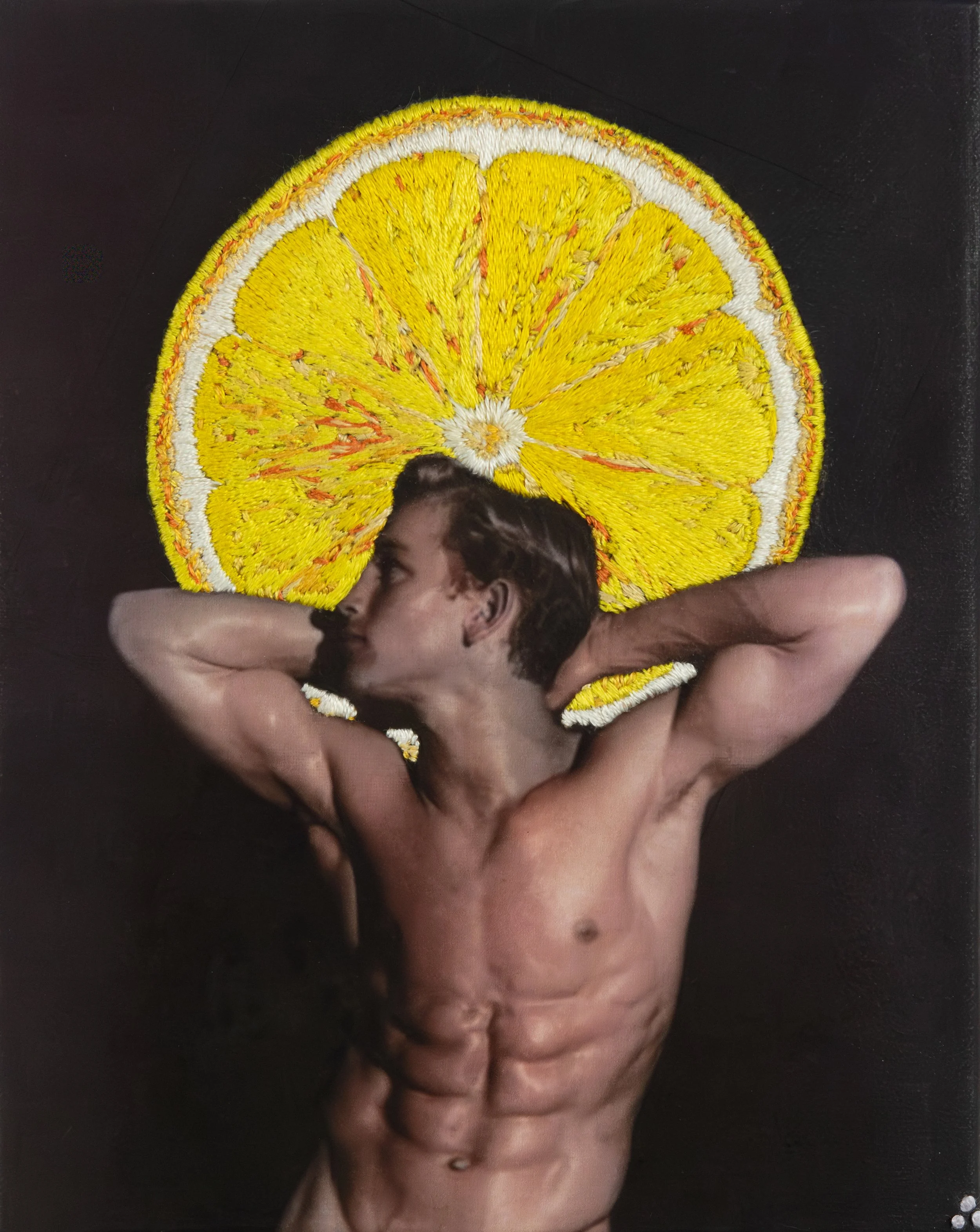 A person’s head is resting on a large, textured lemon slice-shaped embroidery. The embroidery has yellow, white, and orange details, and is arranged in a semi-circle around the head, set against a dark background.