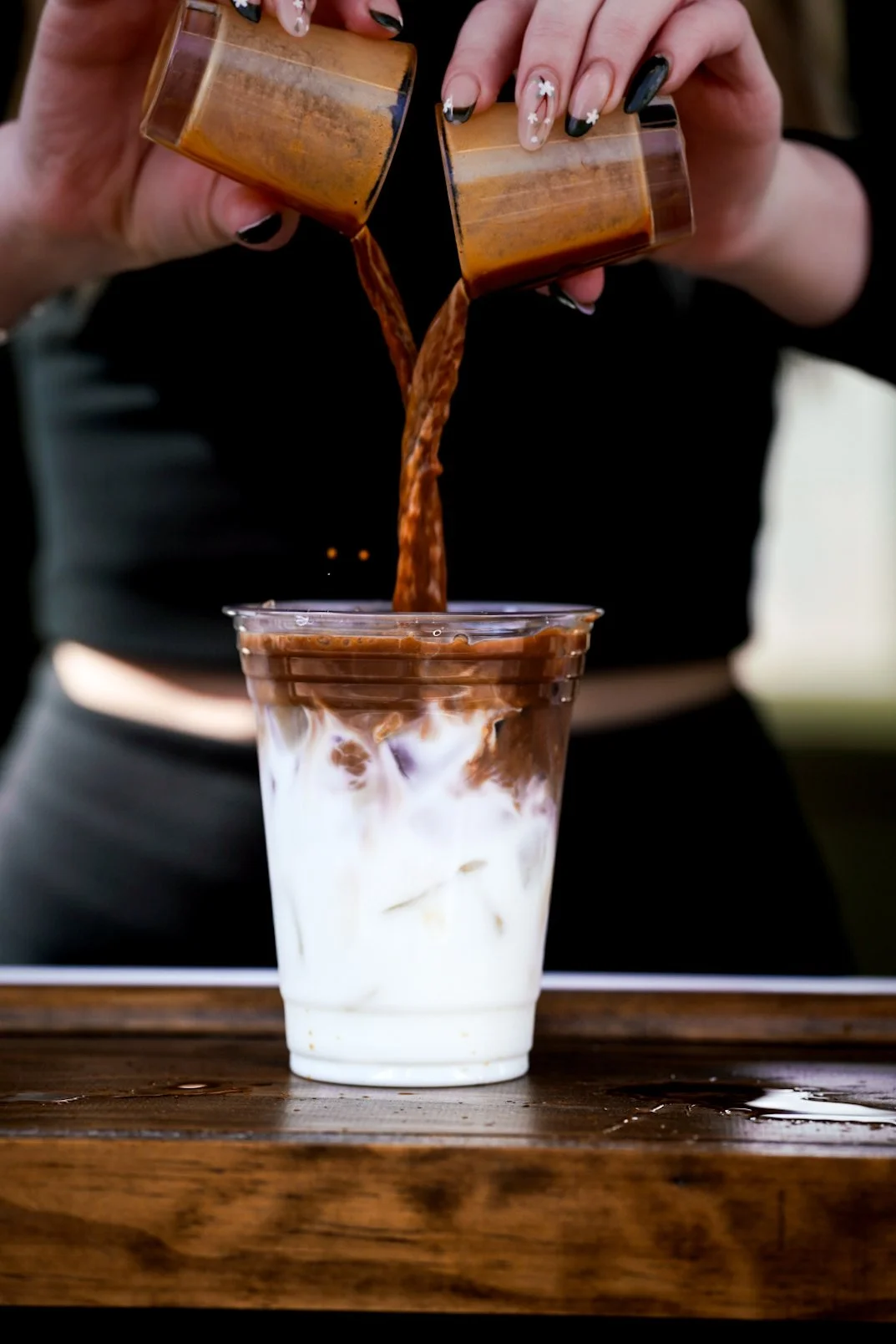 Two espresso shots poured over flavored milk into a 16oz iced coffee to go cup