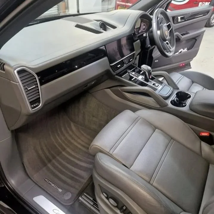 Interior of a modern car showing the driver's seat, dashboard, steering wheel, gear shift, and center console with cup holders.