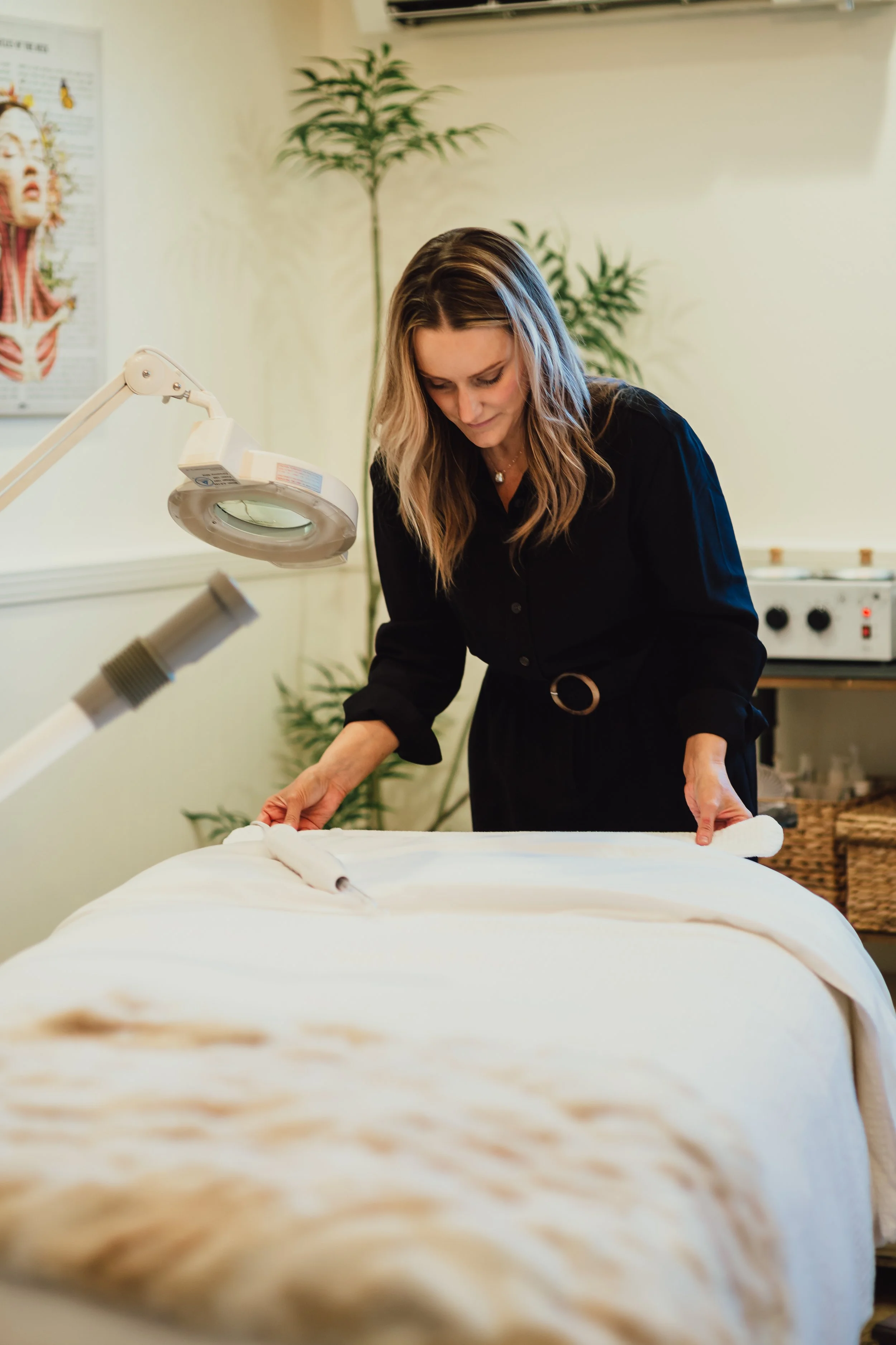 Esthetician preparing luxury spa treatment room for facial service