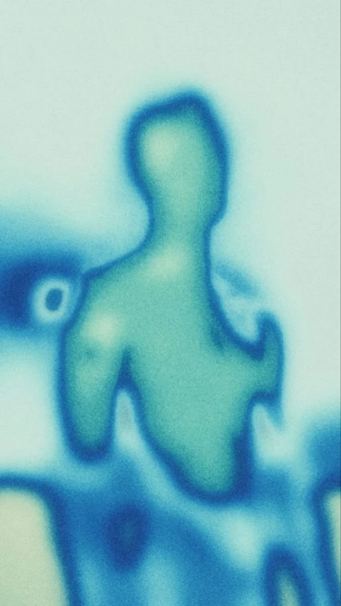 A blurry, sepia-toned silhouette of a child playing with a toy boat on water.