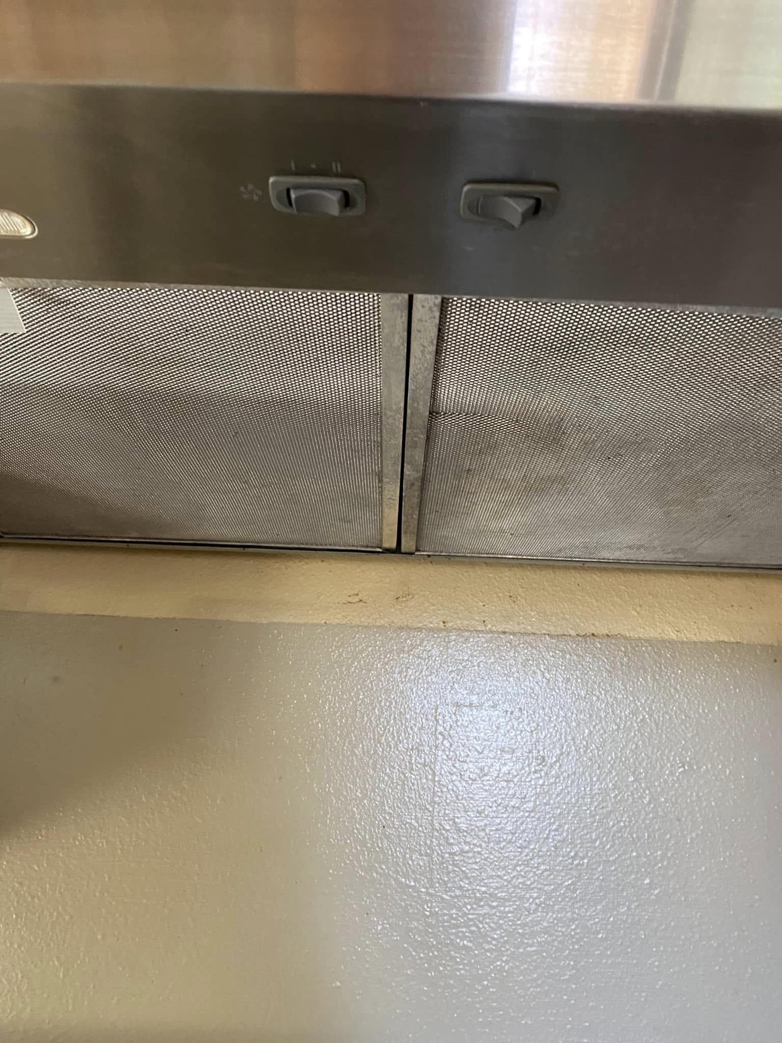 Close-up of a metallic door with two switches on the top, set against a textured metal surface and a painted yellow floor in the background.