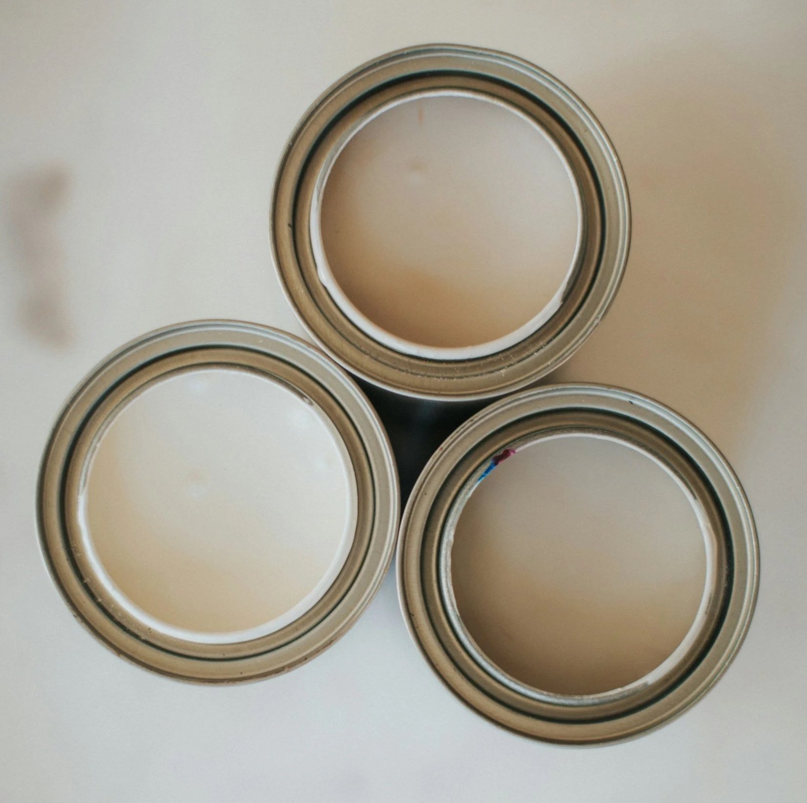 Four cans of paint with open lids, viewed from above, on a white surface.