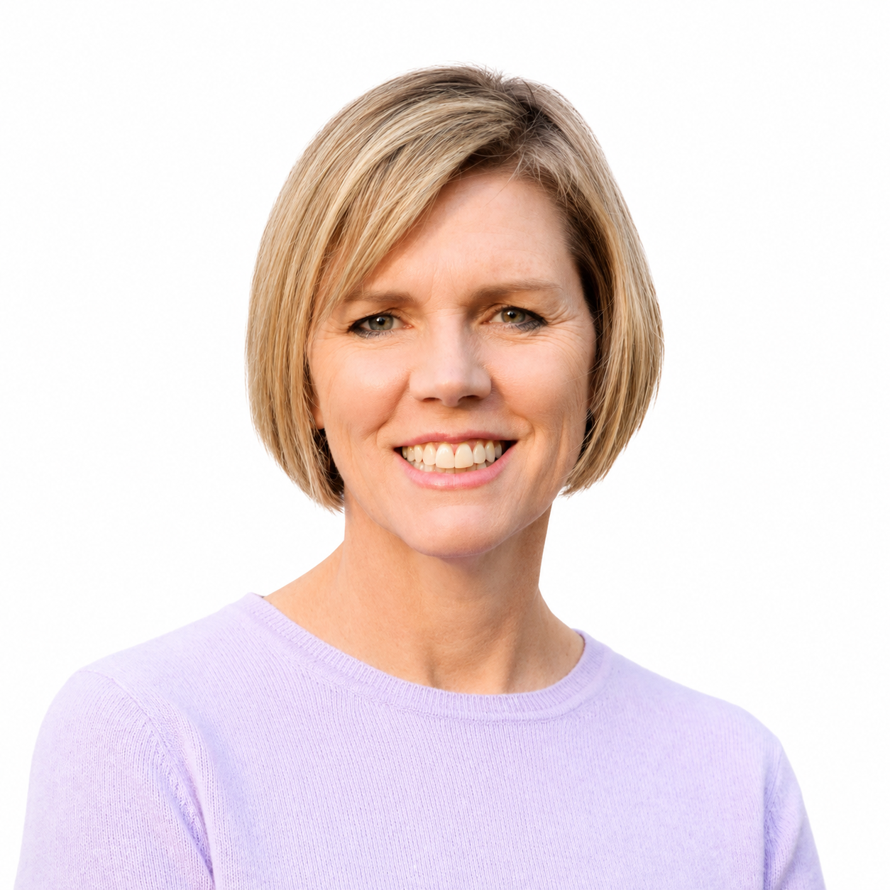 Portrait of a smiling woman with short blonde hair wearing a light purple top against a white background.