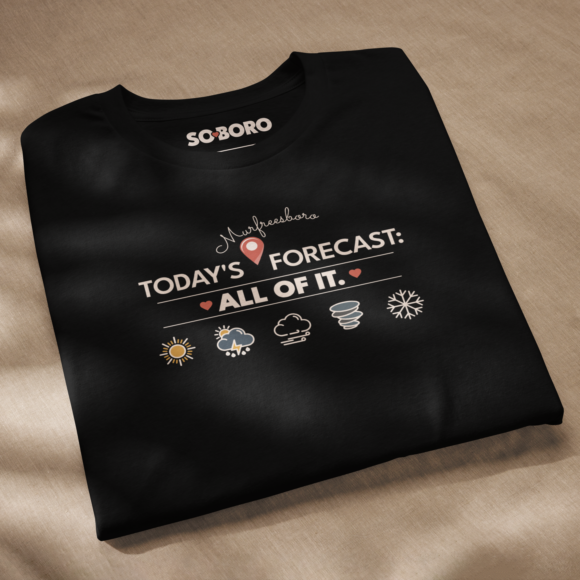 Black T-shirt with a design related to Murfreesboro and weather forecast, lying on a beige fabric surface.
