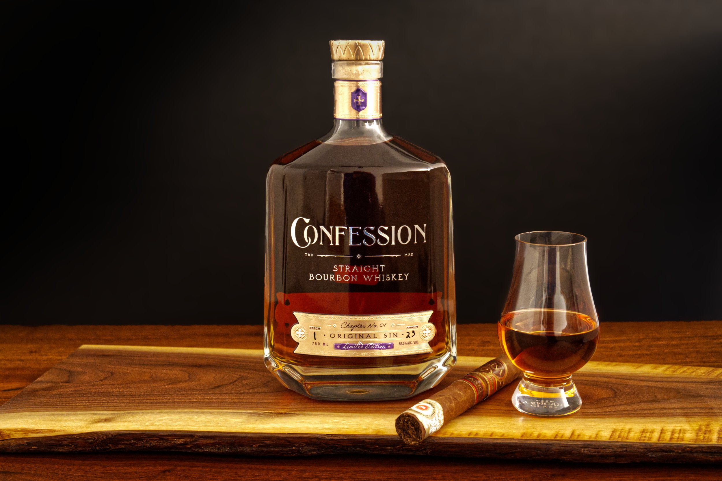 A bottle of Confession bourbon whiskey on a wooden surface, accompanied by a glass of whiskey, and a cigar.