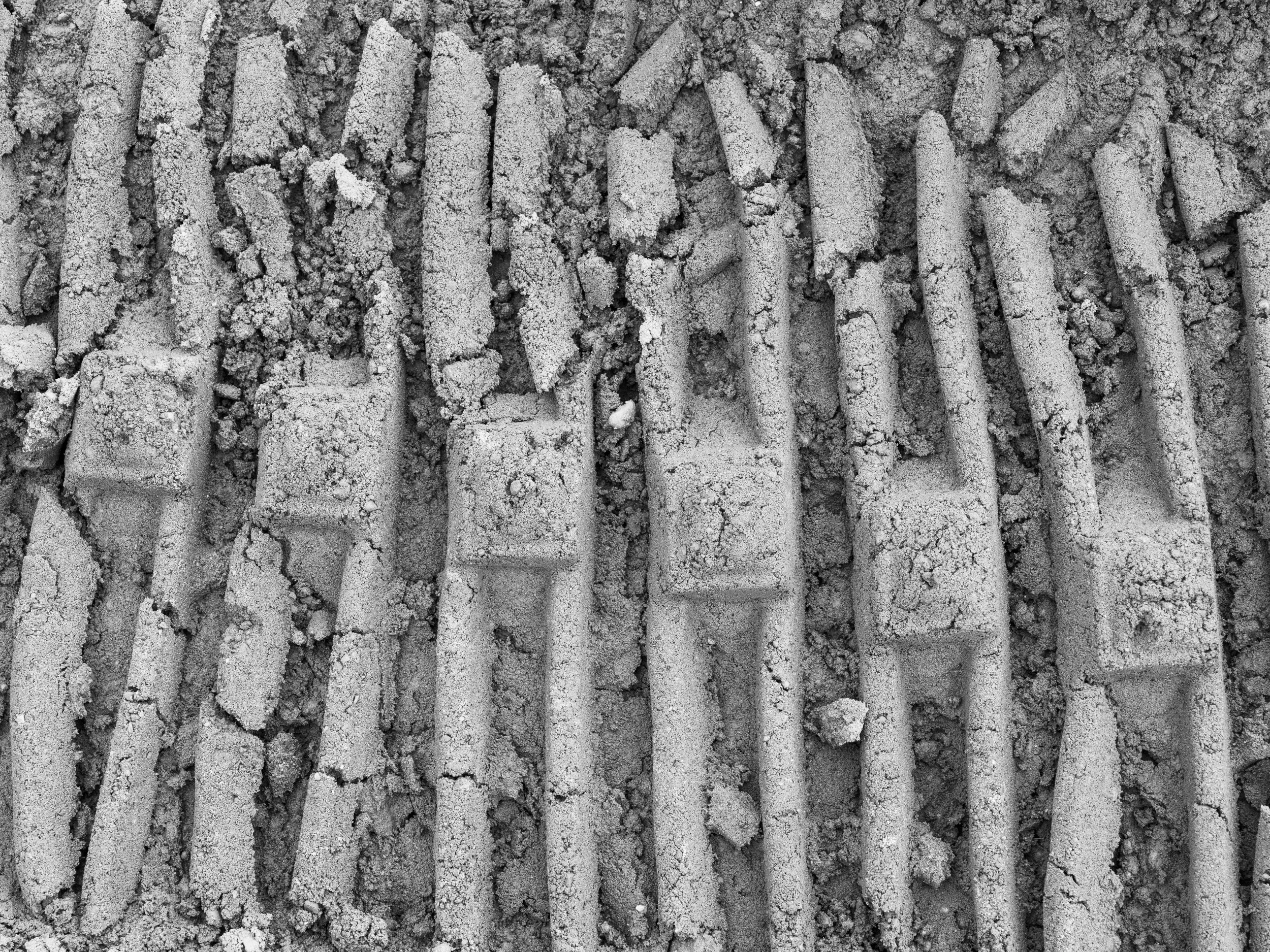 Close-up black and white image of arranged wooden sticks or pieces of wood with some dirt or dust on them.