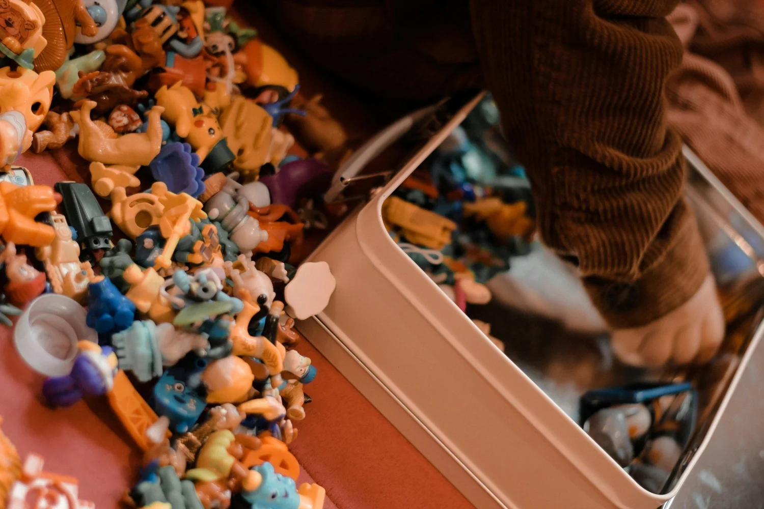 Hands digging through a sensory bin full of colorful toys