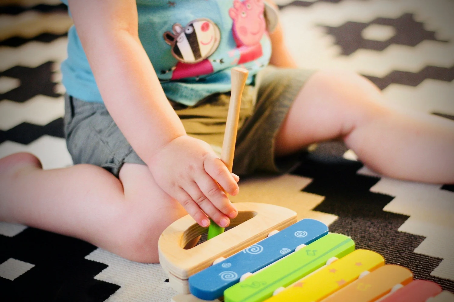 A toddler playing a wooden xylophone toy