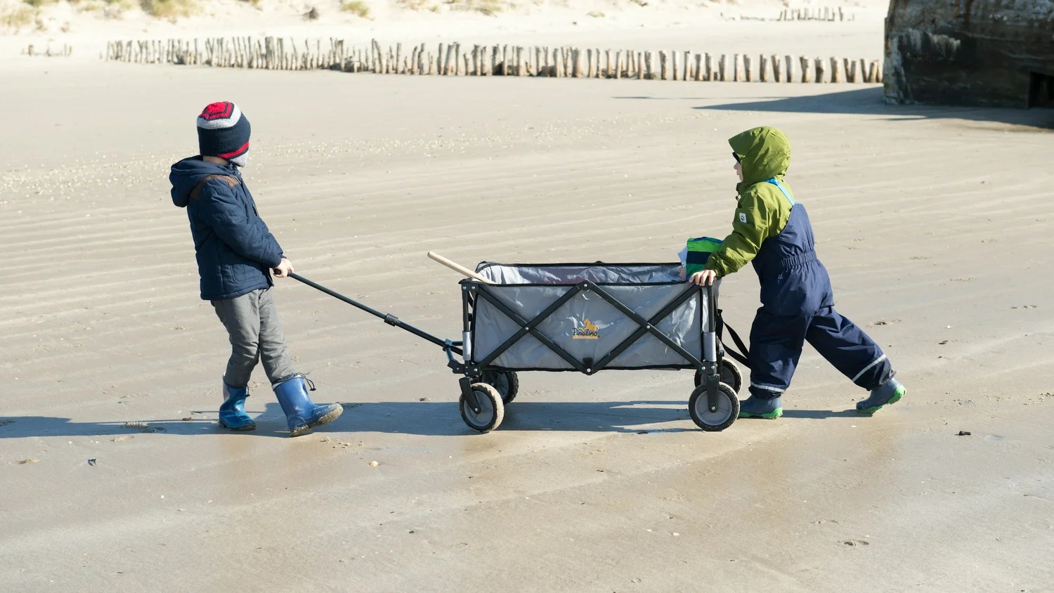 Two children pulling a loaded wagon outside — heavy work play
