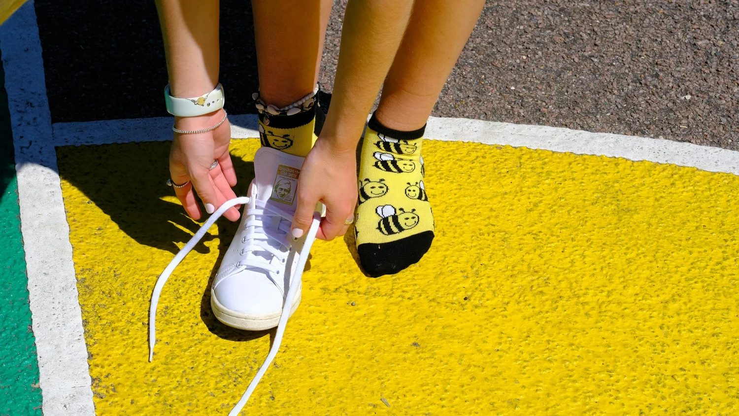 A child's hands tying the laces on a white sneaker