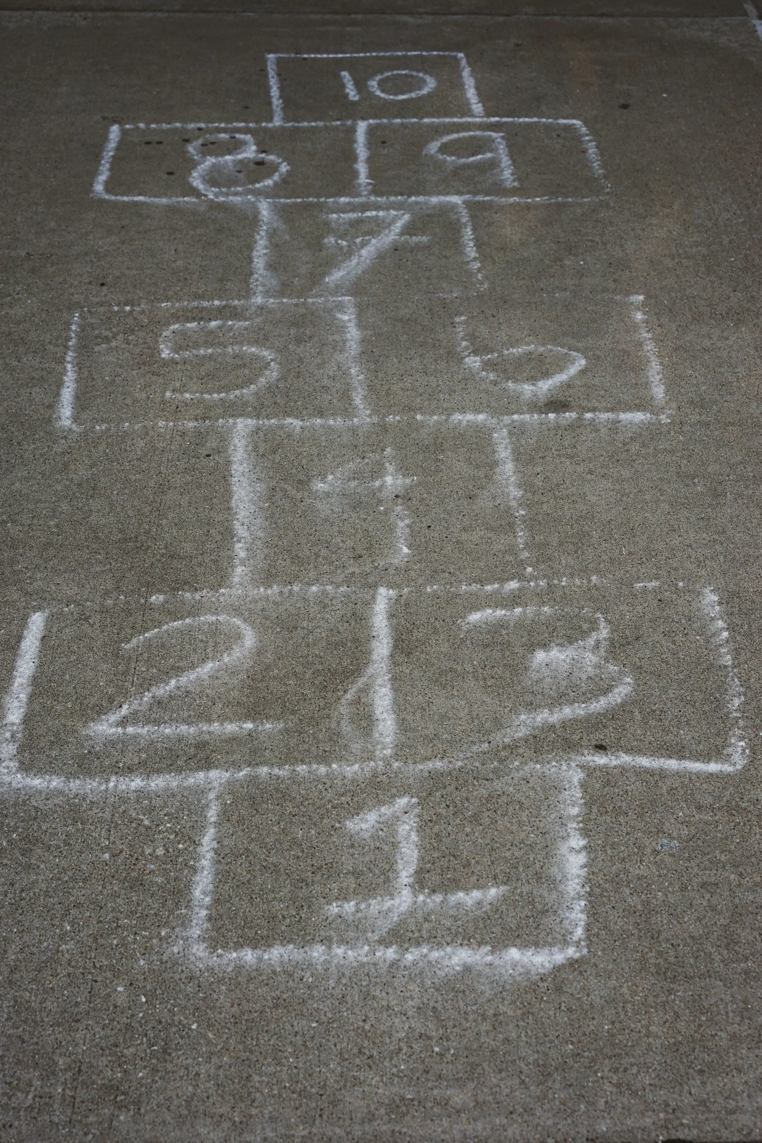 A chalk hopscotch grid with numbers drawn on pavement