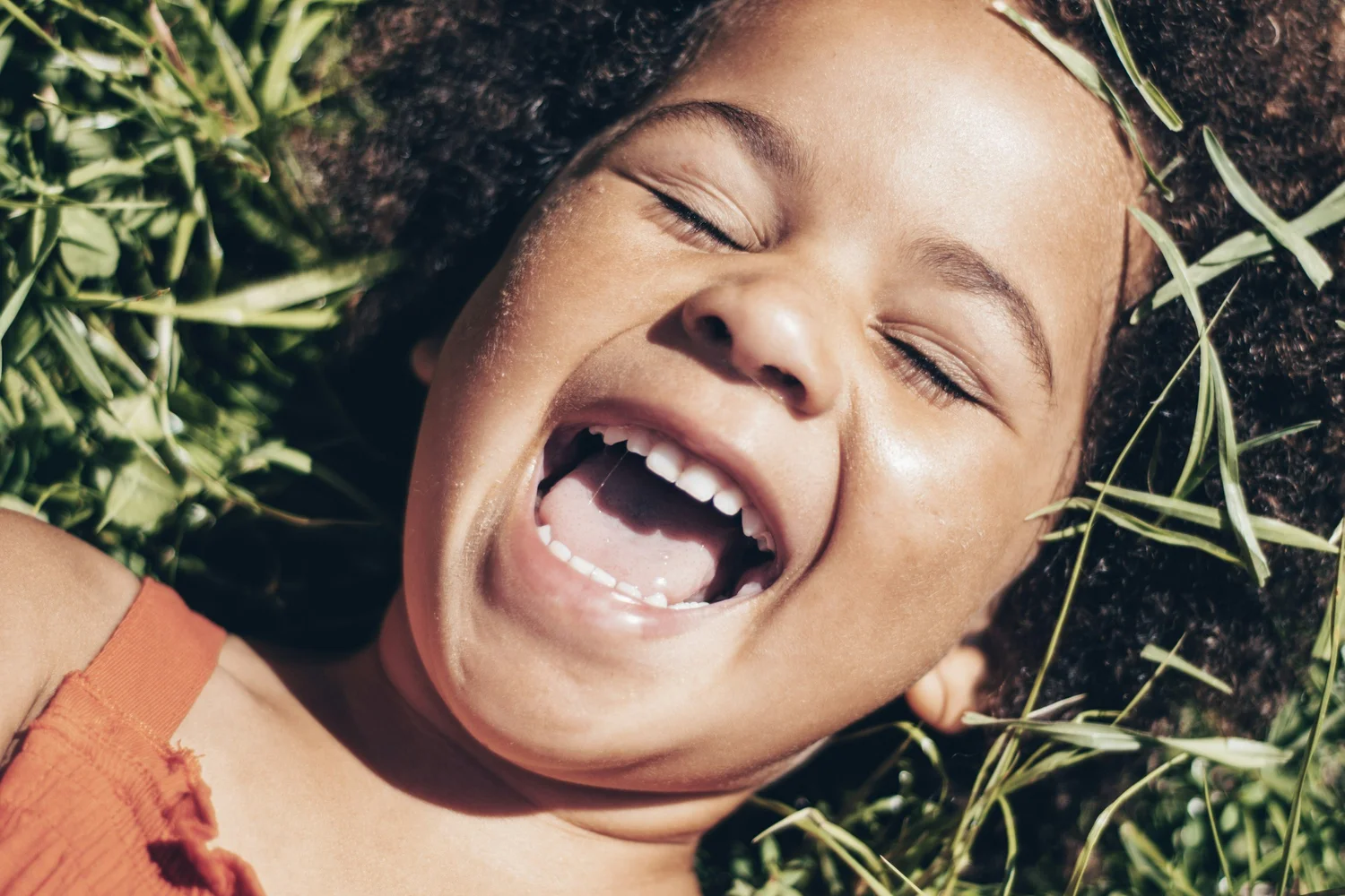 A young child laughing with delight outdoors — big feelings, right out in the open