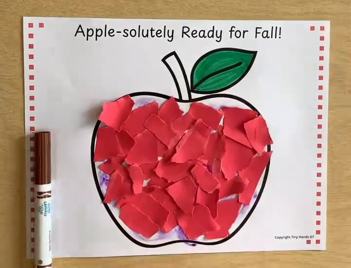 A finished torn-paper fall apple craft with a marker beside it