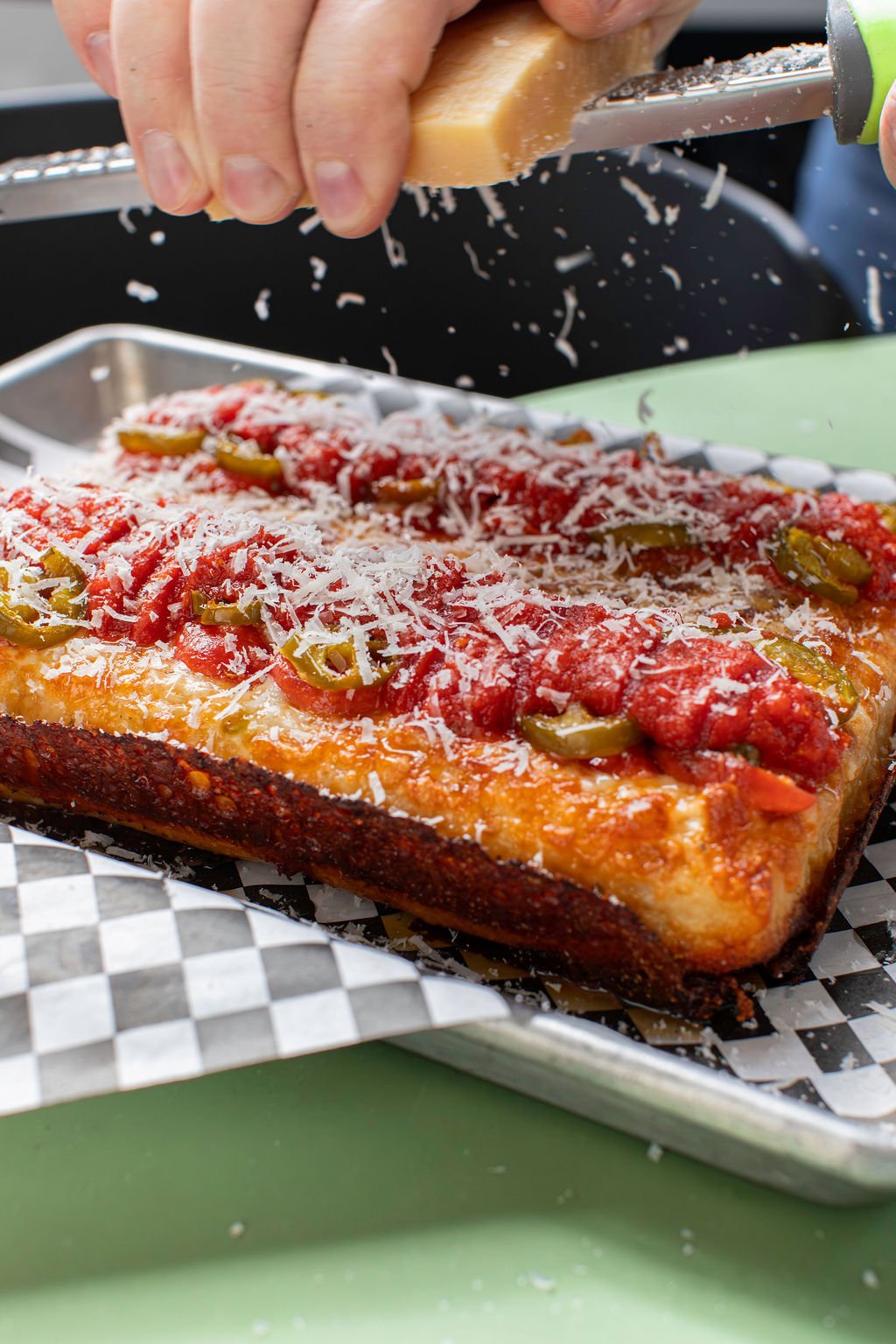 Square pizza close-up: Square Honeycreeper pizza with Grande cheese, pepperoni, pickled jalapenos, Cali vine-ripened tomato sauce, caramelized cheese skirt, finished with Mike's Hot Honey