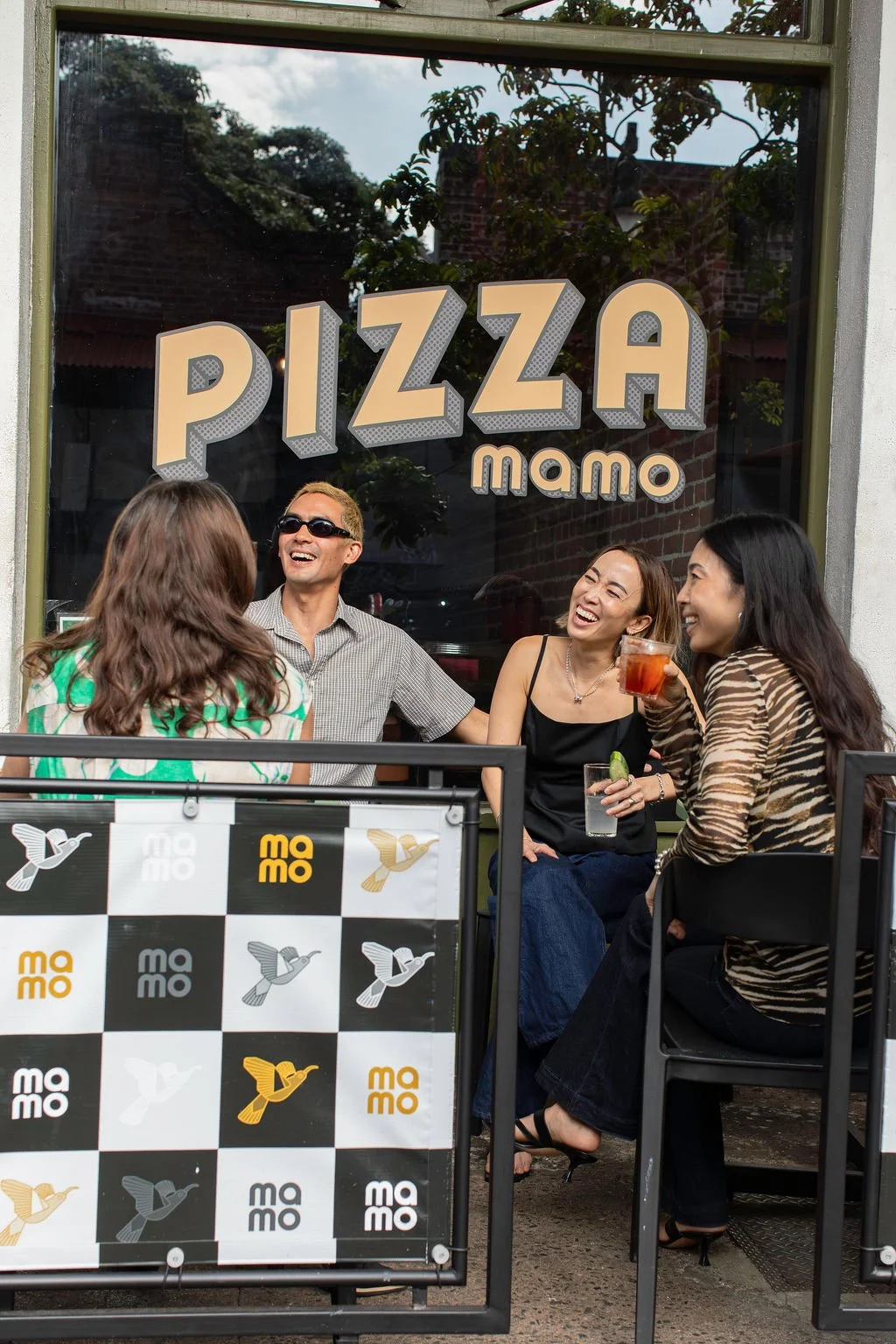 Group of friend enjoying Pizza Mamo squares and rounds pizzas at a outdoor patio table in Honolulu