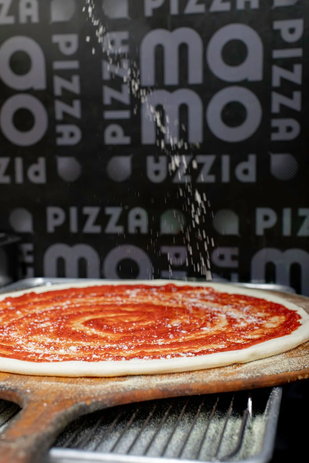 Round pizza being prepared for the oven at Pizza Mamo