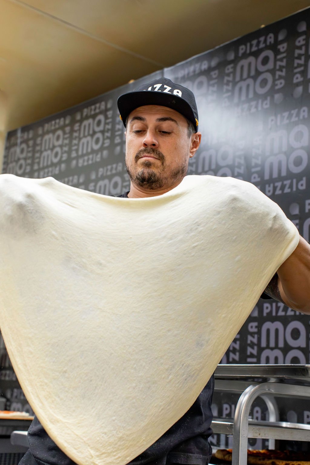 Pizza Mamo team member stretching pizza dough by hand