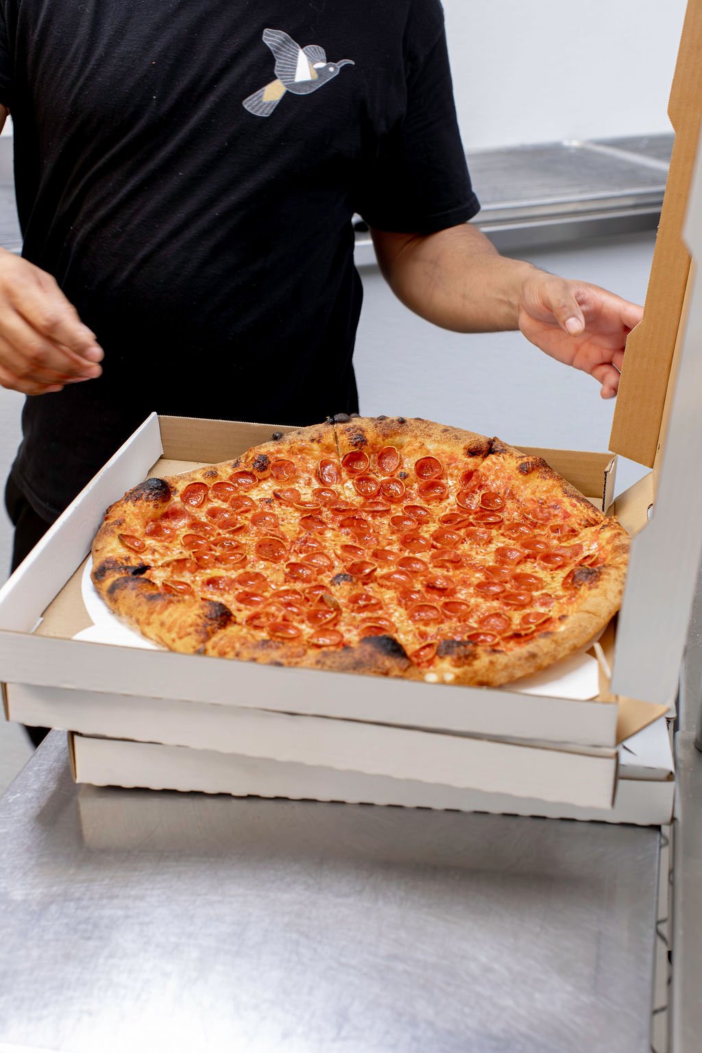 Pizza Mamo round pizza being boxed for pickup or delivery