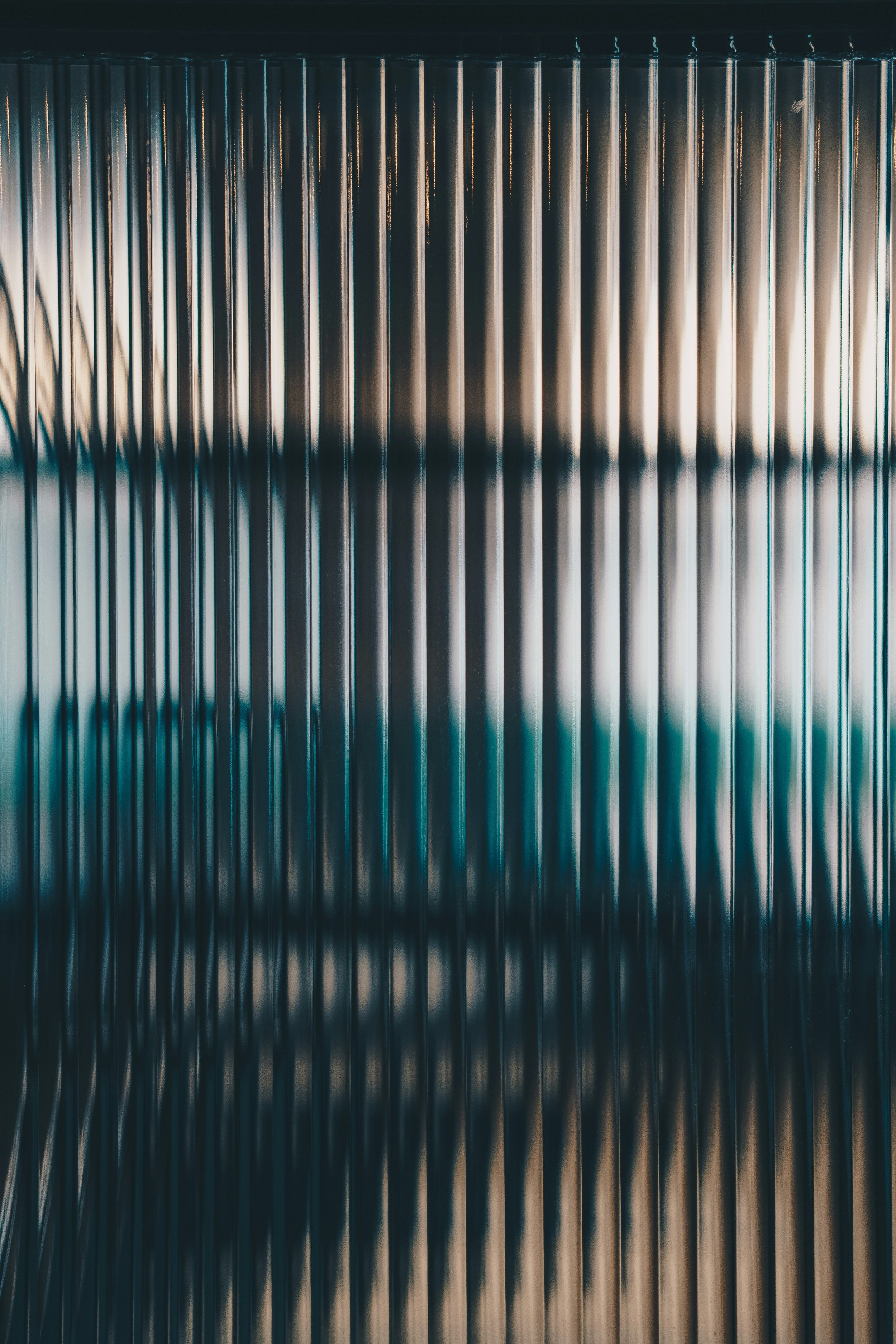 Close-up of metallic vertical industrial pipes, with reflections and darker background.