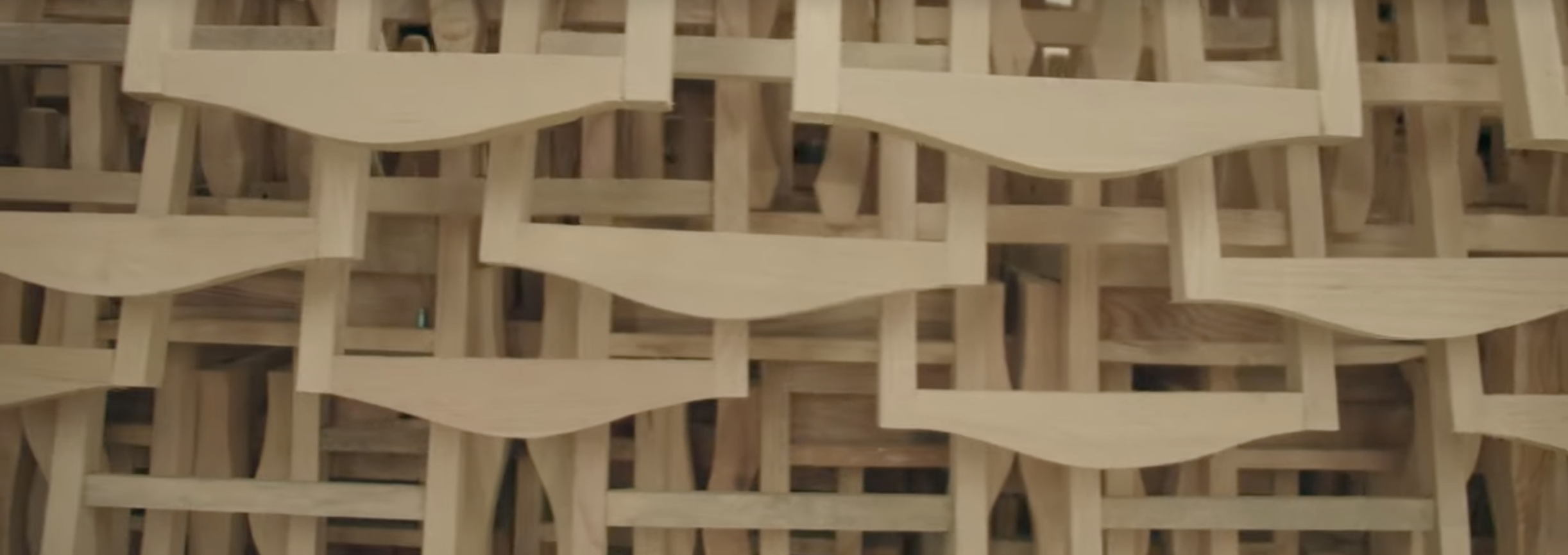 Close-up view of a woven wooden chair back with an intricate interlaced pattern of light-colored wood strips.