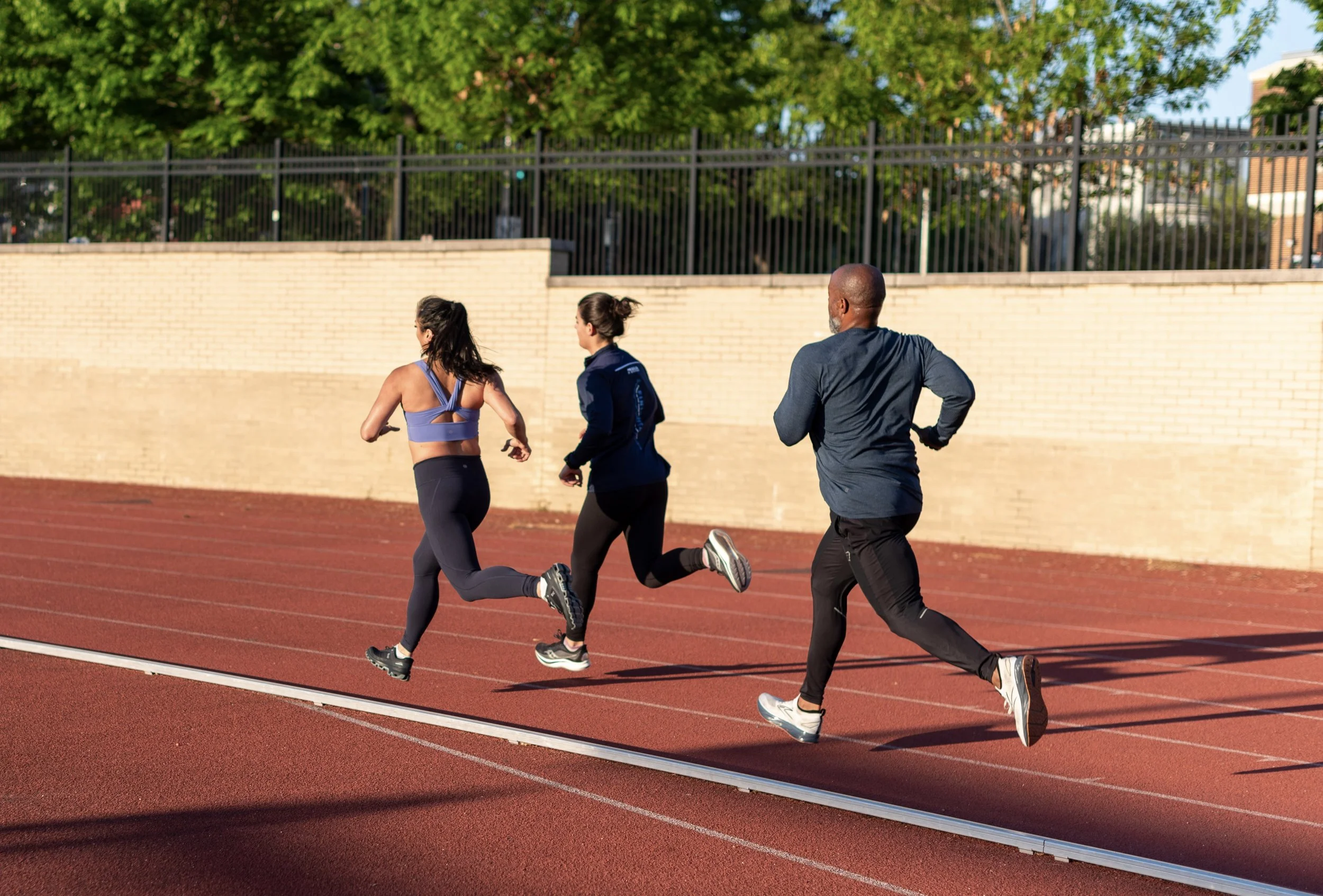 Physical therapist providing running assessment and coaching for runners on an outdoor track.