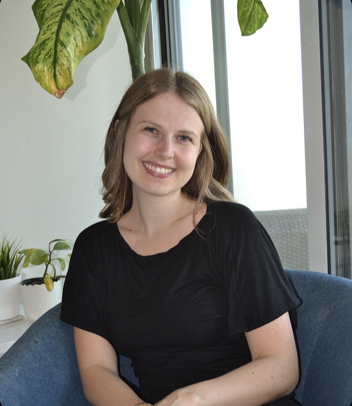 Lauren Weake, Registered Psychotherapist (Qualifying) and founder of BridgeWell Therapy, smiling while seated in a bright office.