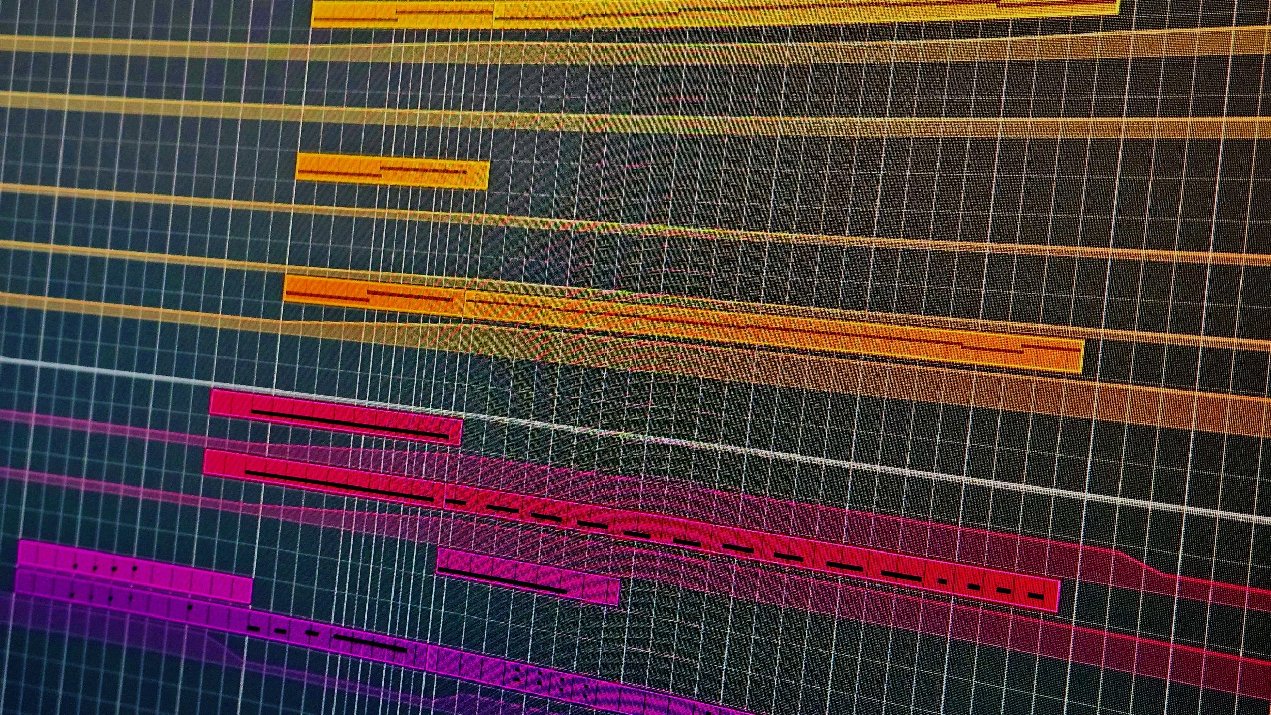 A digital audio workstation screen displaying a colorful, layered track timeline with various audio clips in bright colors such as pink, orange, yellow, and purple, arranged horizontally on a dark grid background.