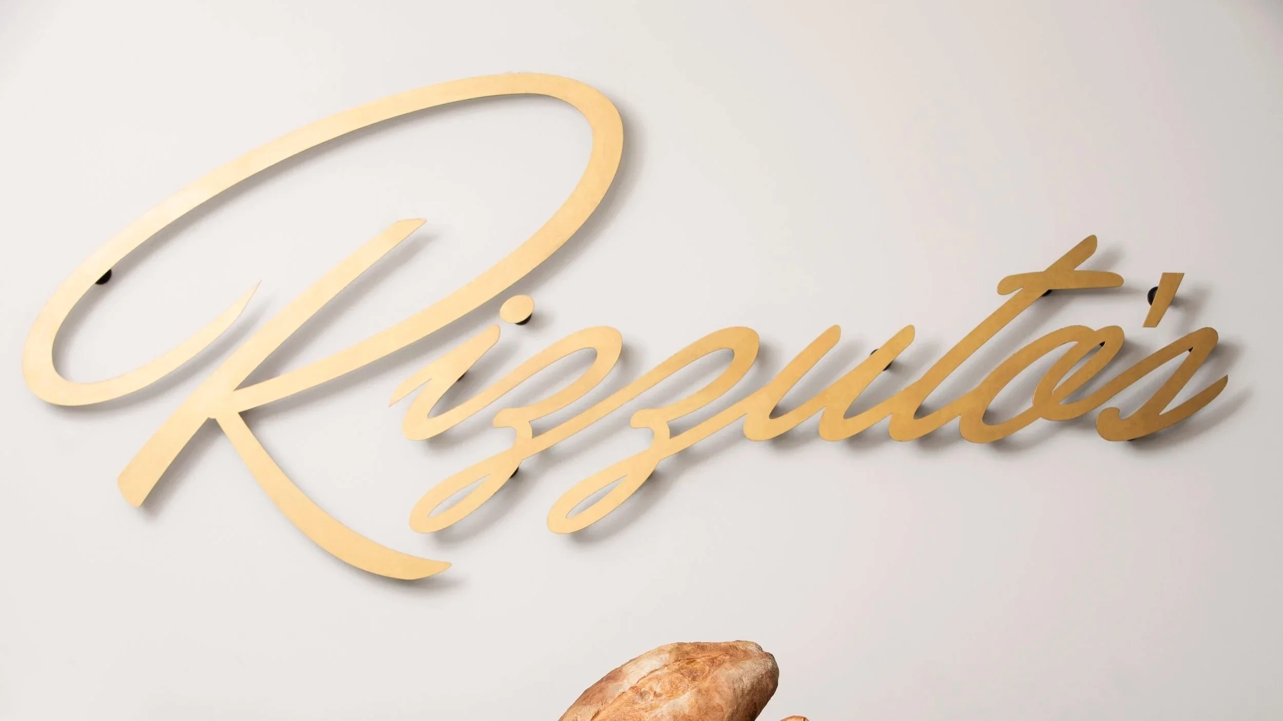 Close-up of a wall decoration with gold cursive text and a bread roll below.