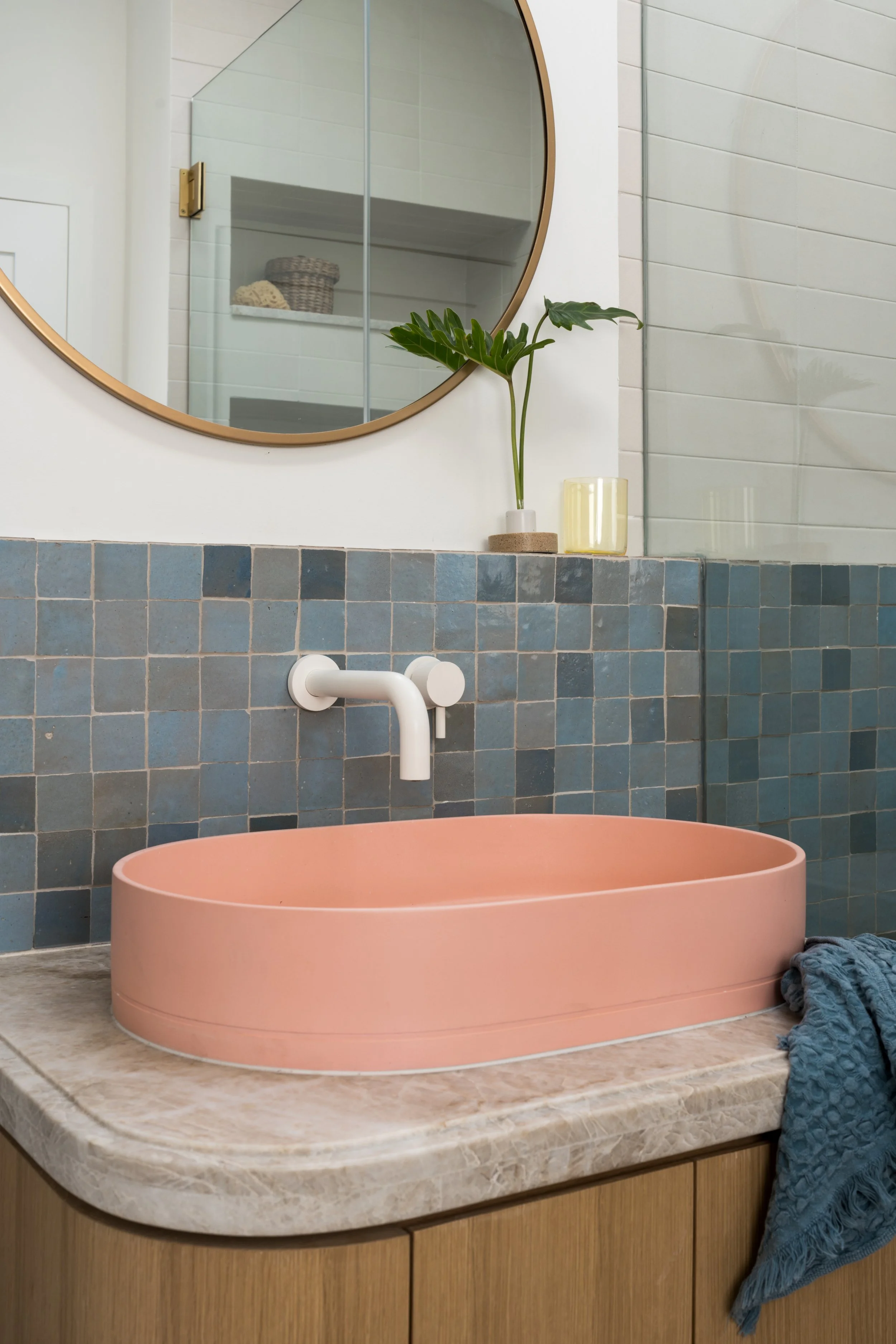 Close-up of pink sink and white metal faucet against blue tile.