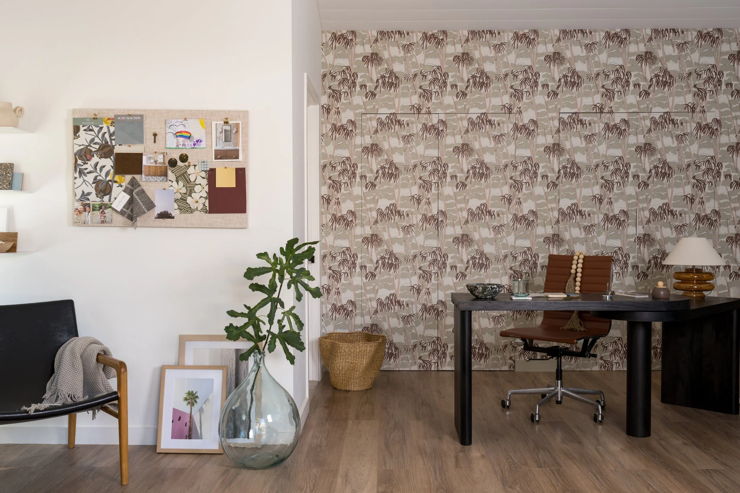 ADU space featuring wallpapered back wall with desk set-up and a styling area with a black chair in the foreground.