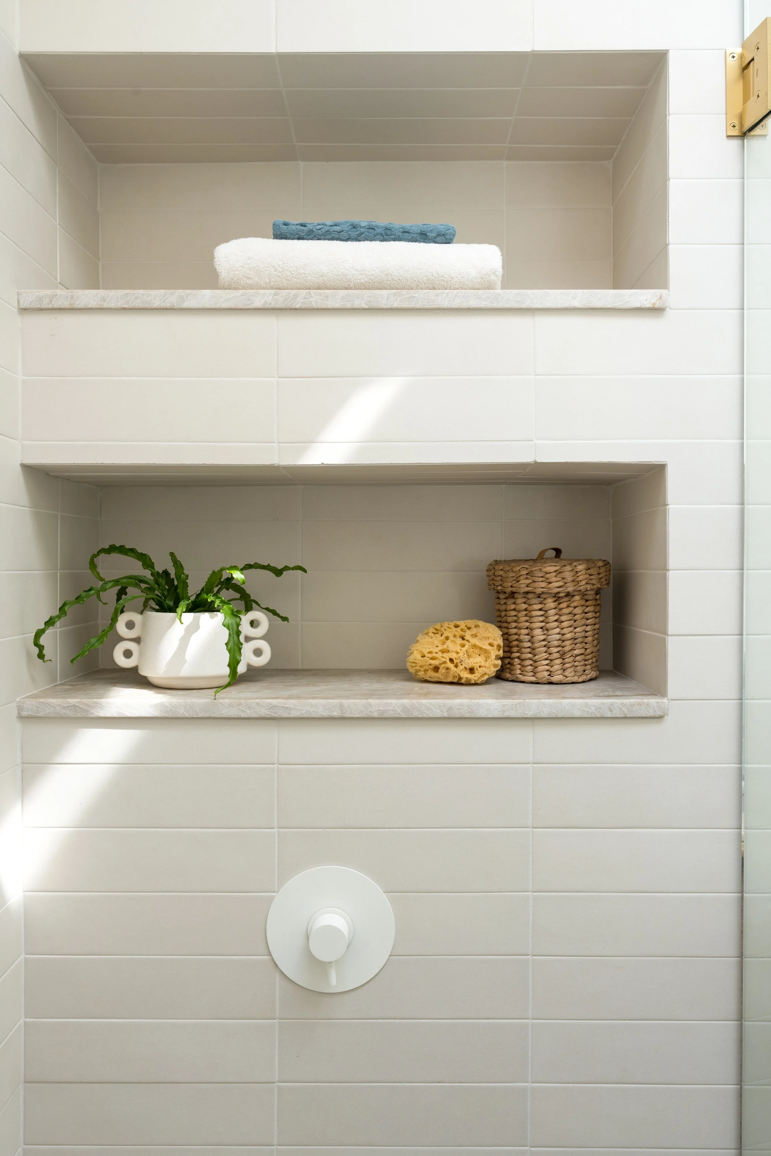 Close-up of shower tile niches with white shower valve below.