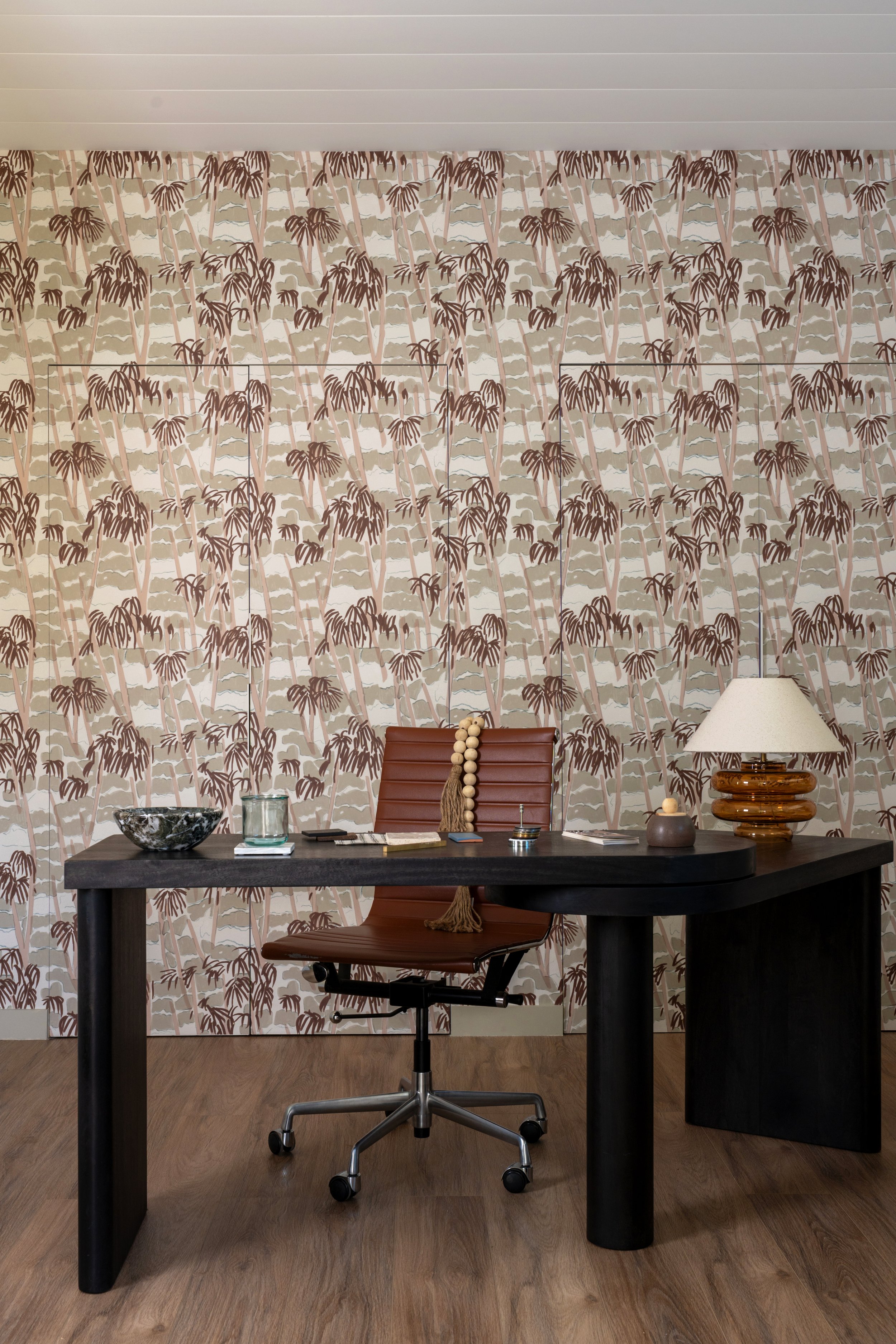 View into ADU interior with patterned wallpaper on the back wall and desk set-up in the foreground.