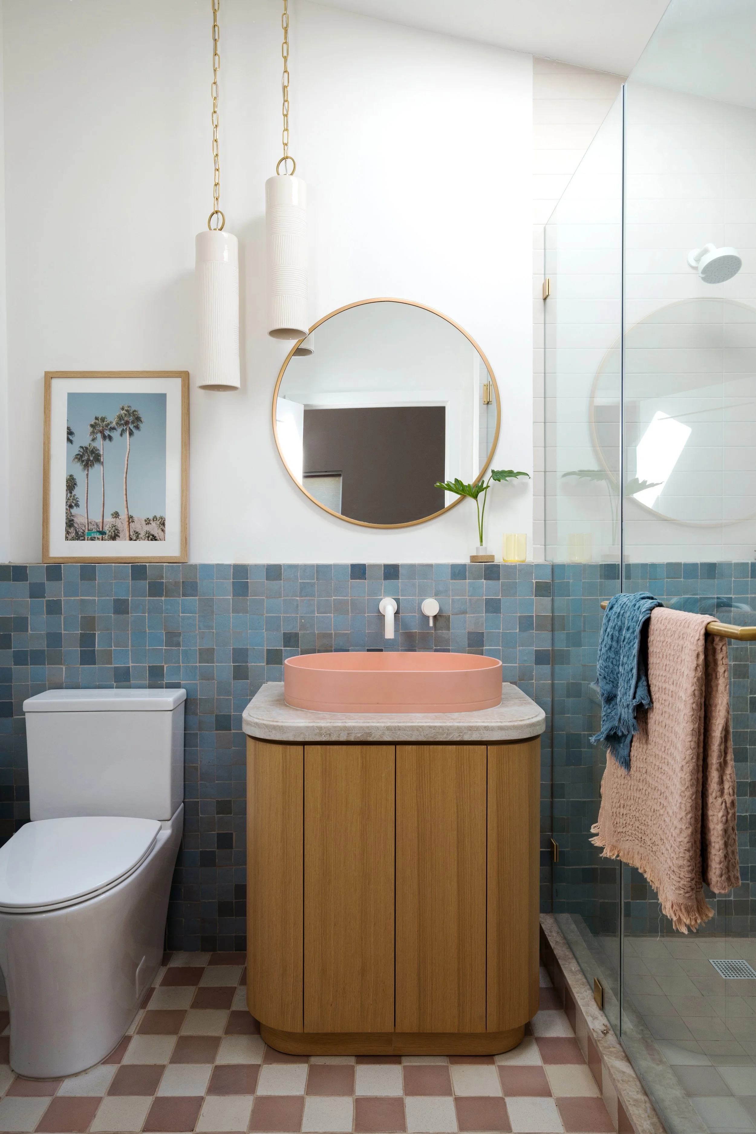 Bathroom with blue, pink, and cream tile walls, a wood vanity, and a pink sink with playful, colorful details throughout.