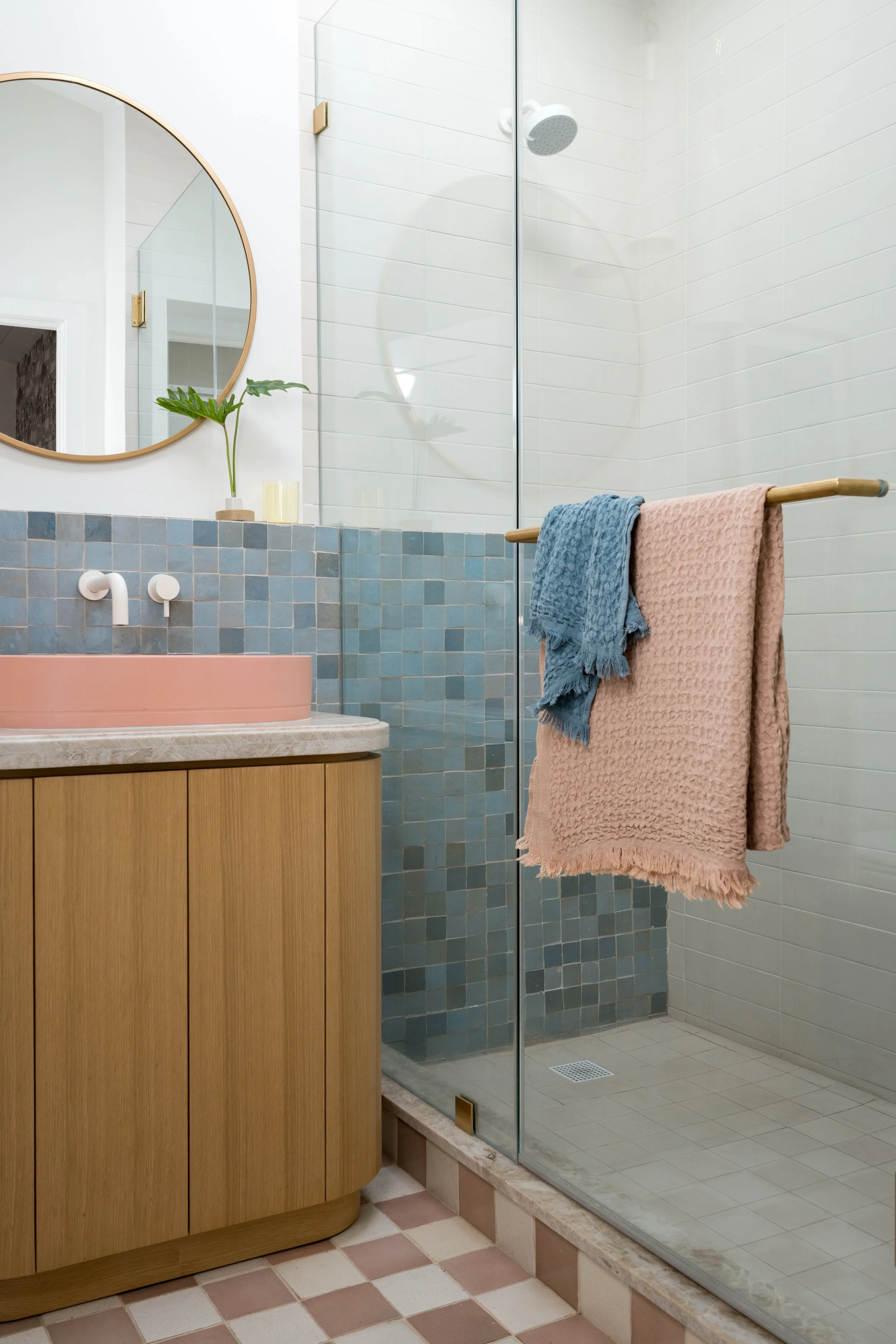 Shower area featuring blue and cream tile with playful pink accents.
