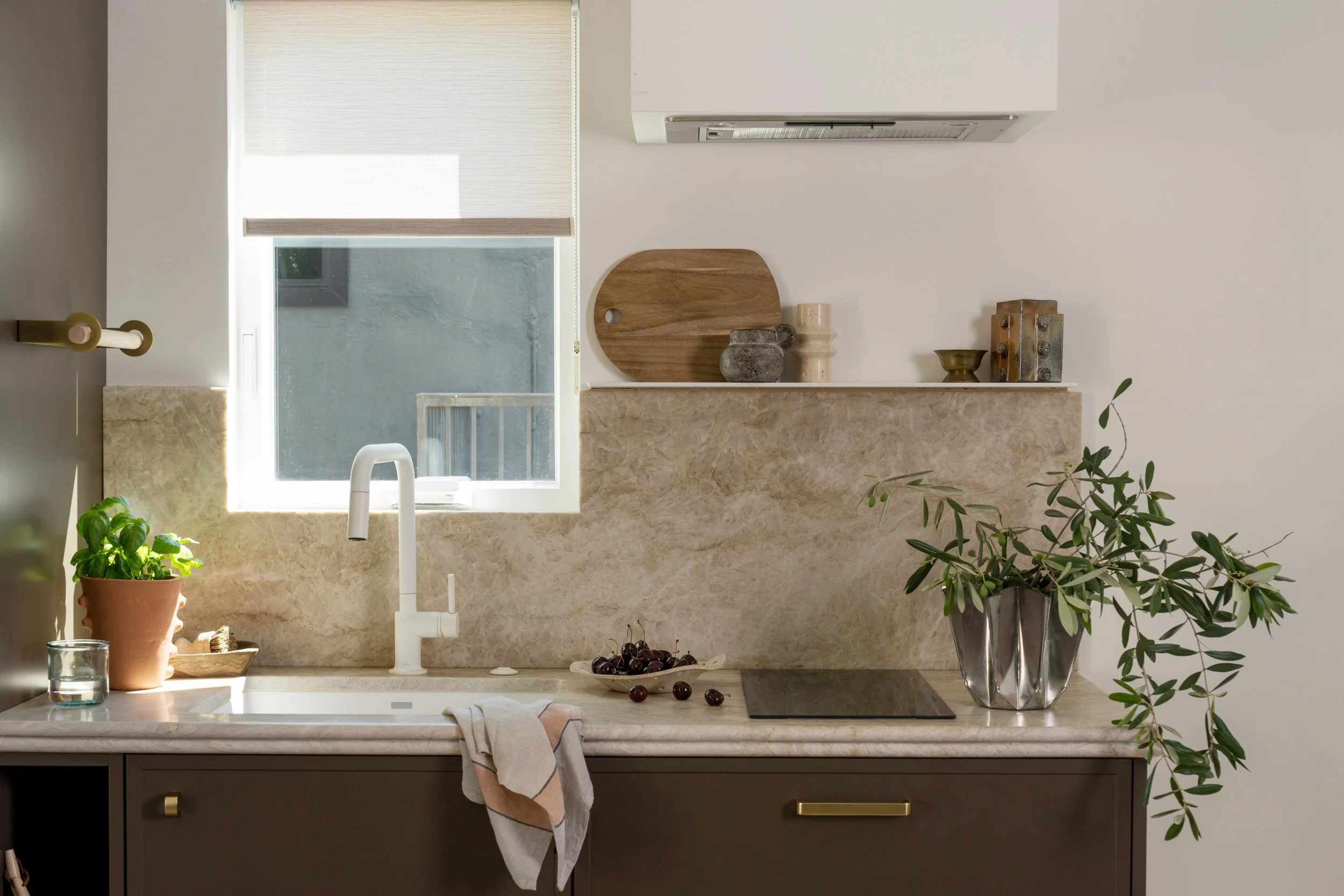 Kitchen featuring brown wood cabinetry, white faucet, and a continuous stone countertop and matching stone backsplash.