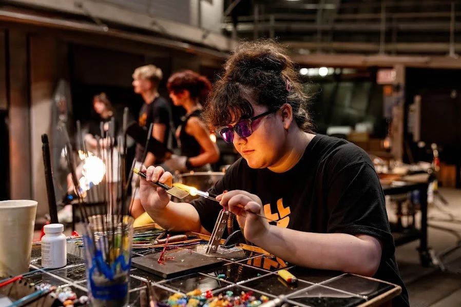 Photograph of high school age girl wearing protective eyewear and soldering something in an art studio