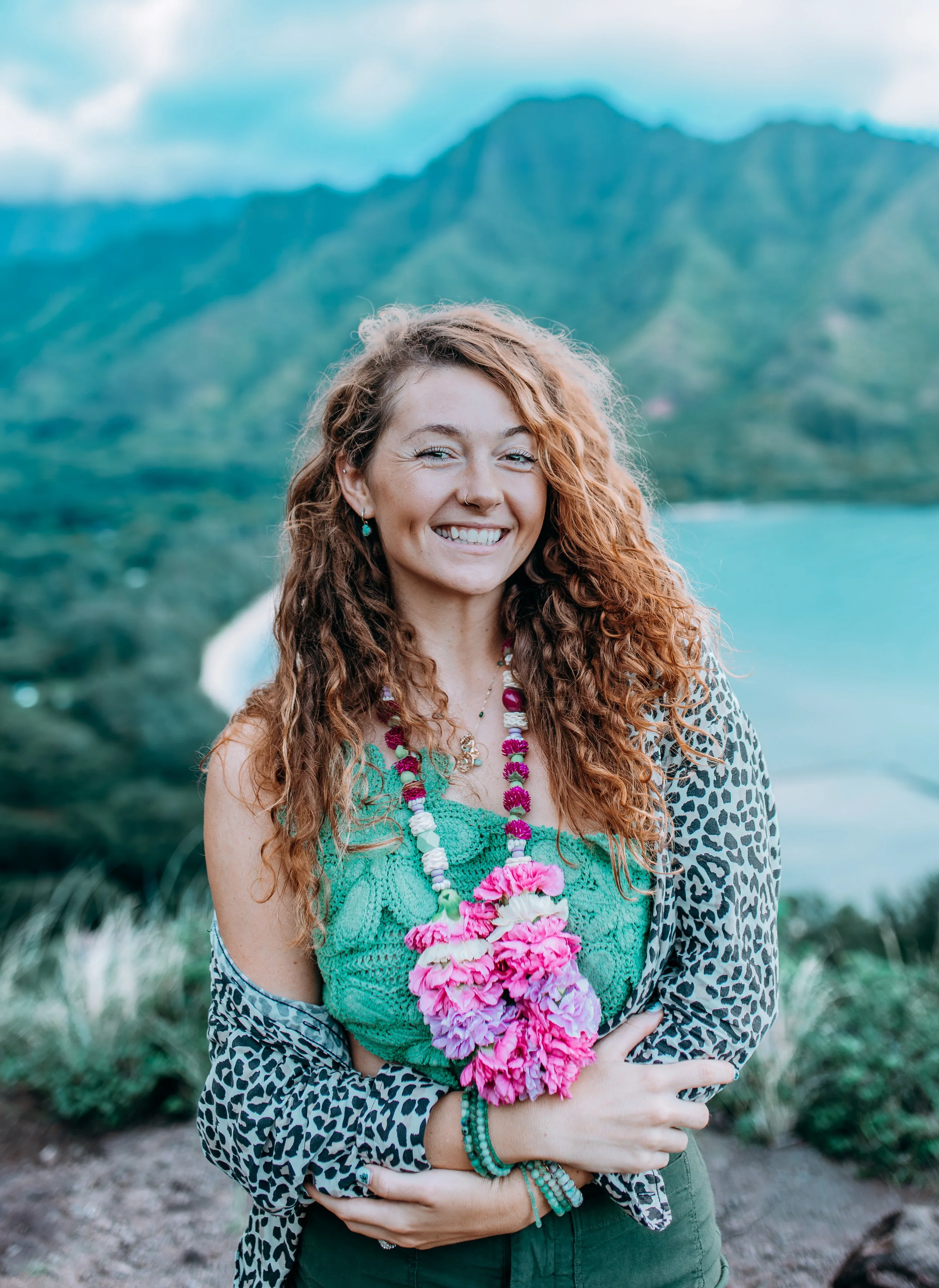 Portrait of Emarie, founder and photographer of Flora & Femina, photographed outdoors with lush Oʻahu mountains in the background.