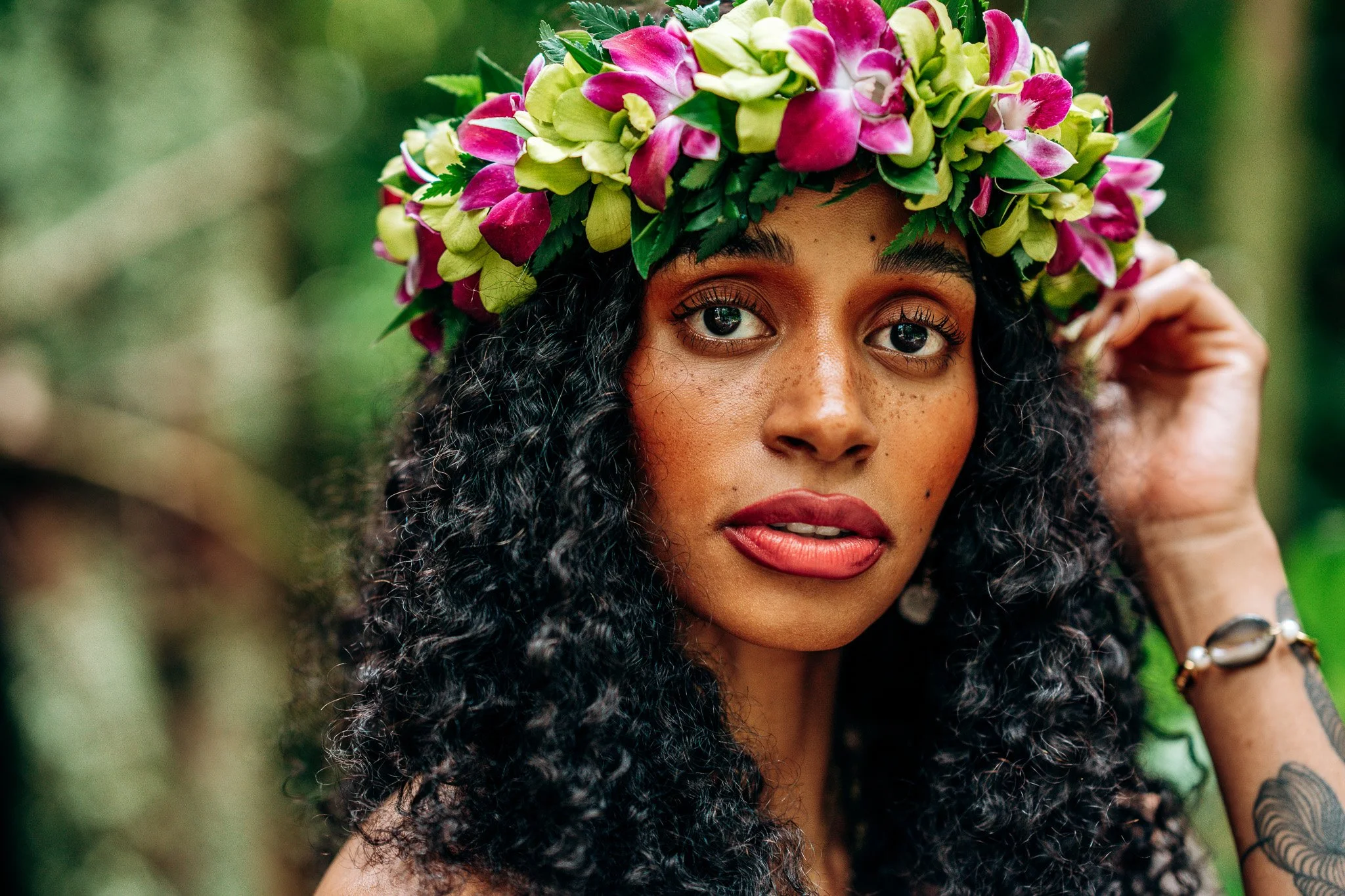 Floral portrait of a woman wearing a colorful Hawaiian flower crown with a soft tropical background during a Flora & Femina portrait session.