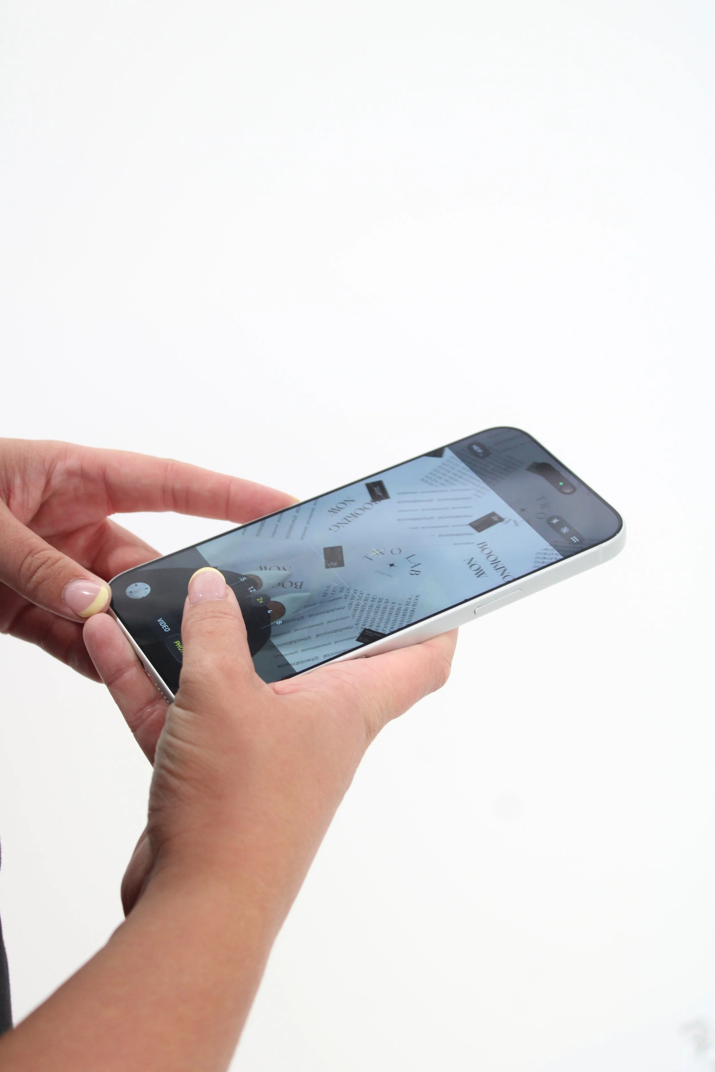 A person holding a smartphone, taking a photo of Two Lab Social flyers on the ground.