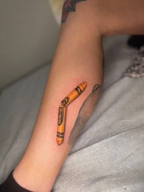 Tattoo of a crayon on an inner forearm.
