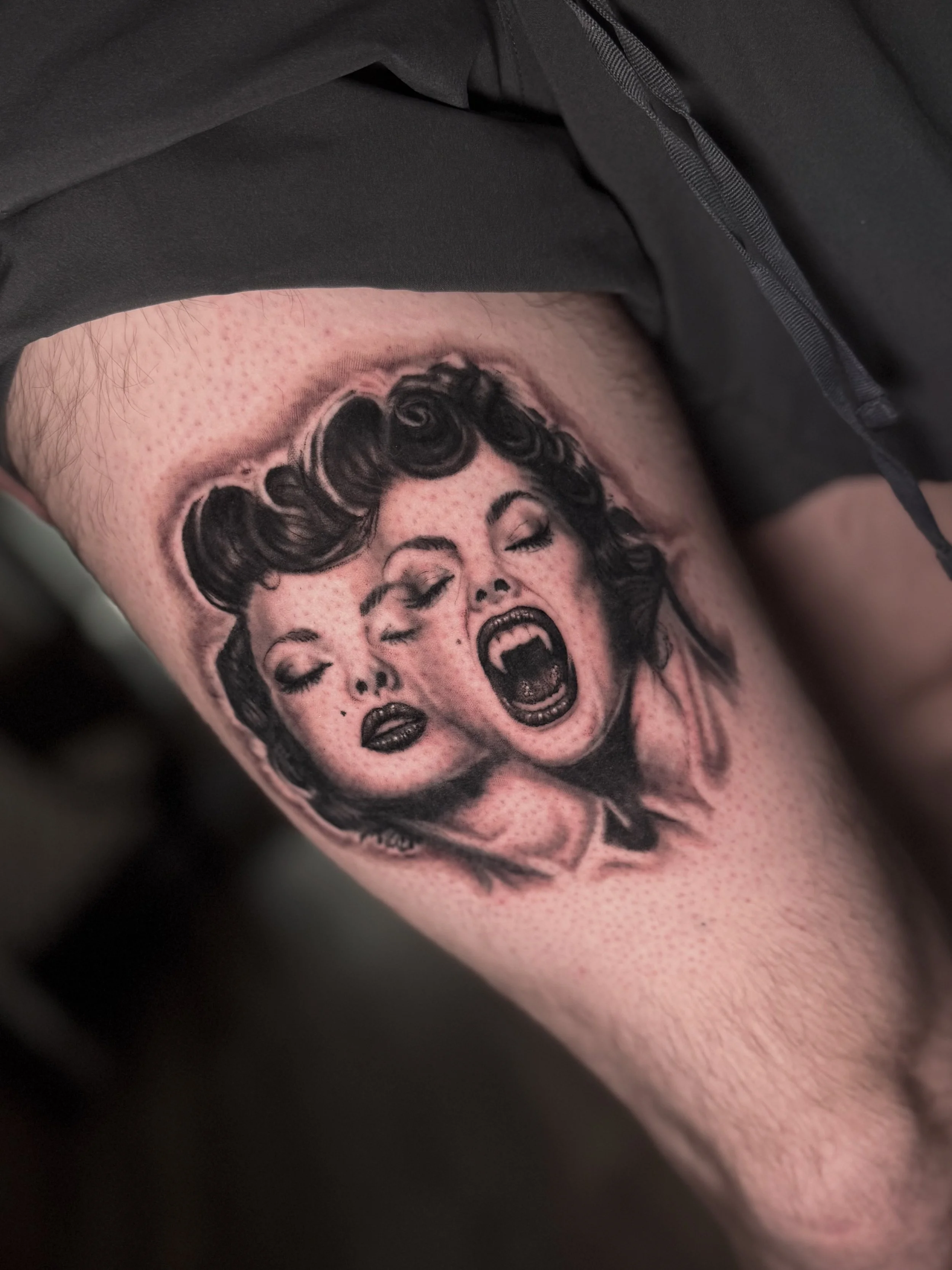 Black and gray tattoo of a woman's face with a vintage hairstyle, with her eyes closed and mouth open as if shouting, on a person's arm.