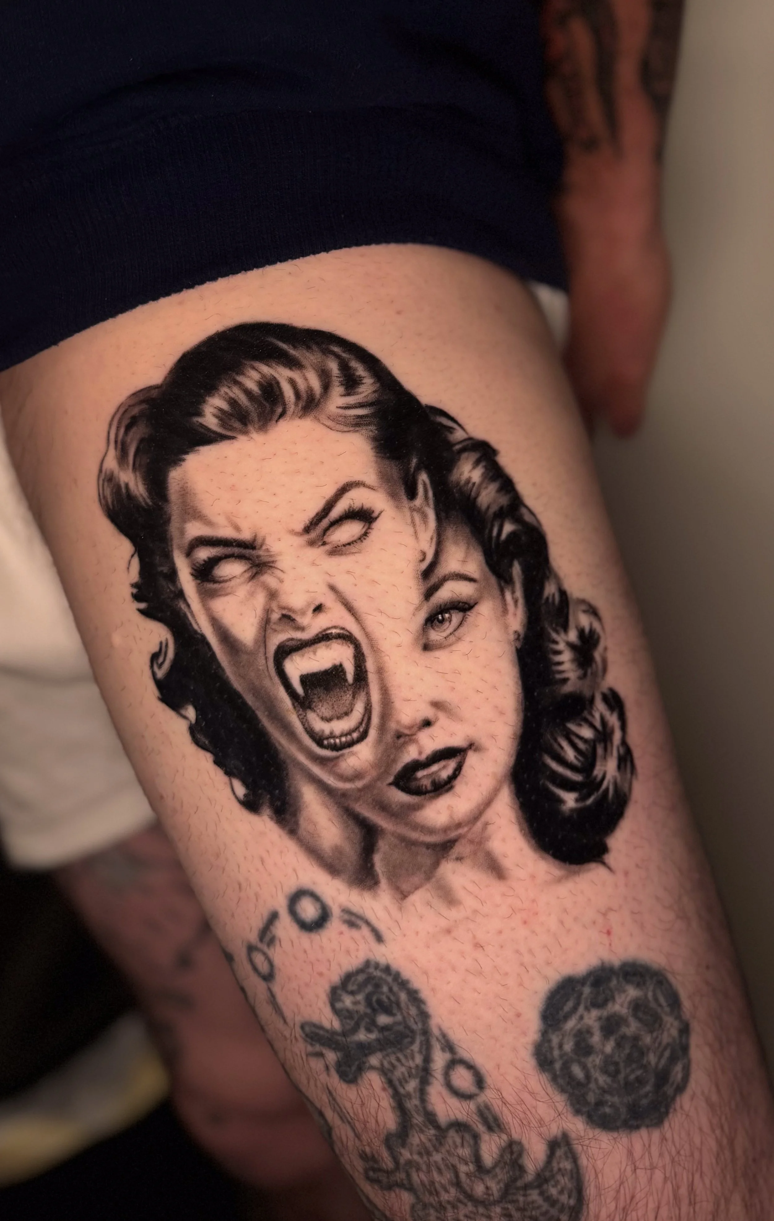 Tattoo of a woman with a fierce expression, her mouth open in a roar, and cartoonish eyes, on a person's arm.