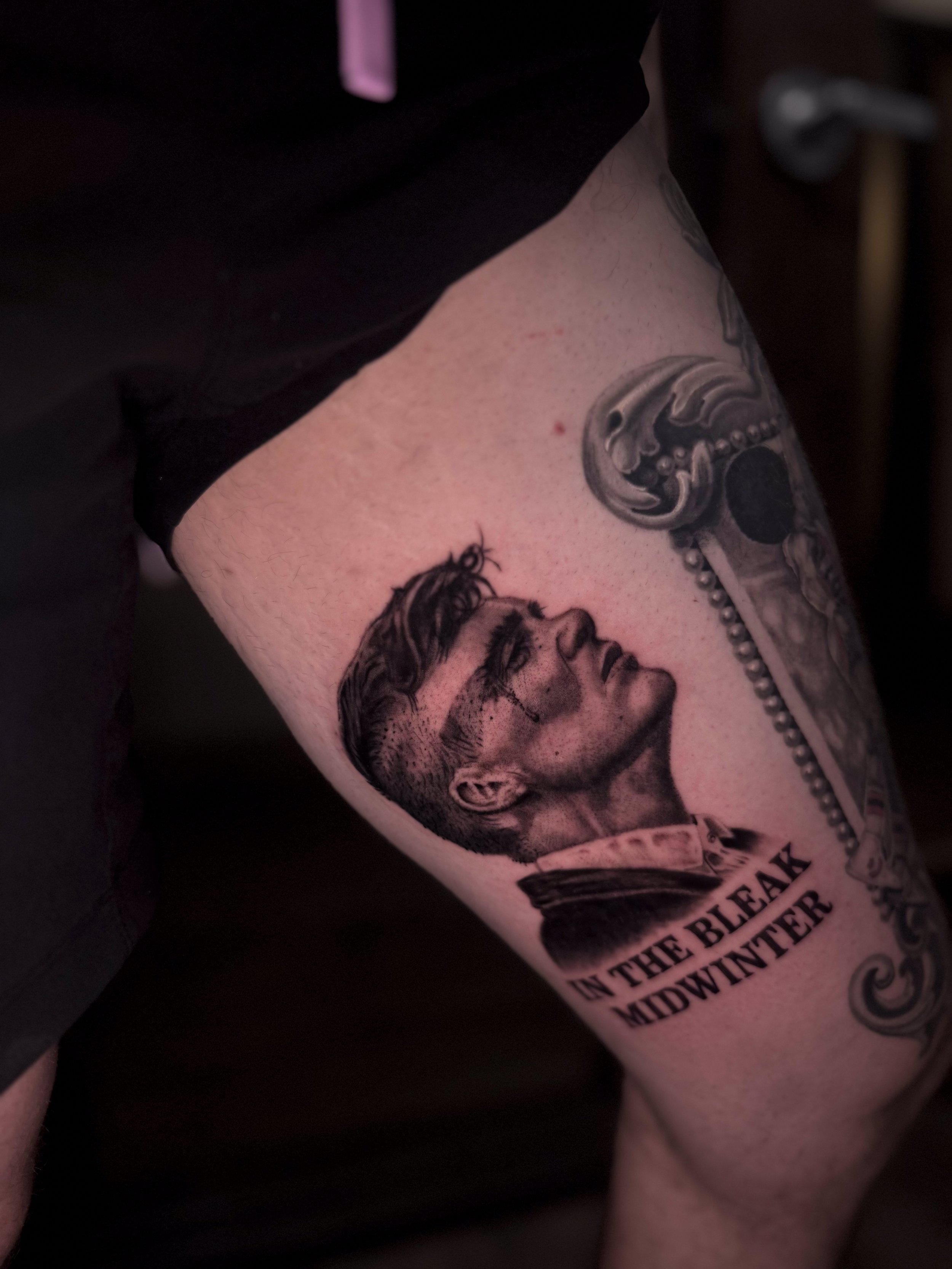 Close-up photo of a tattoo on a person's arm depicting a woman's face and part of a dollar bill with the text "THE BREAK IN THE MIDWEST".