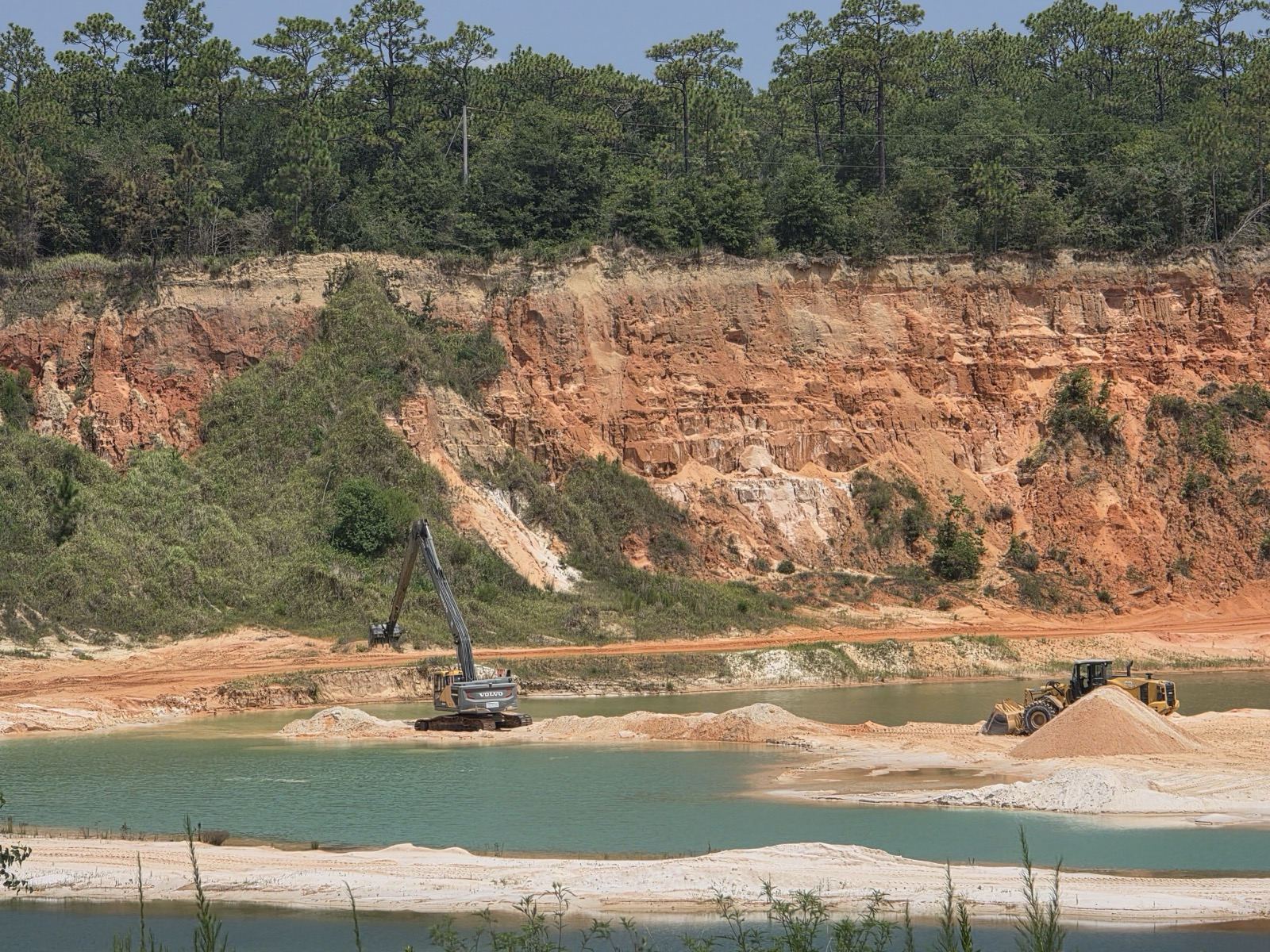 Excavator and loader moving fill dirt at the NOBL Sitework pit at 3125 River Rd in Navarre, Florida
