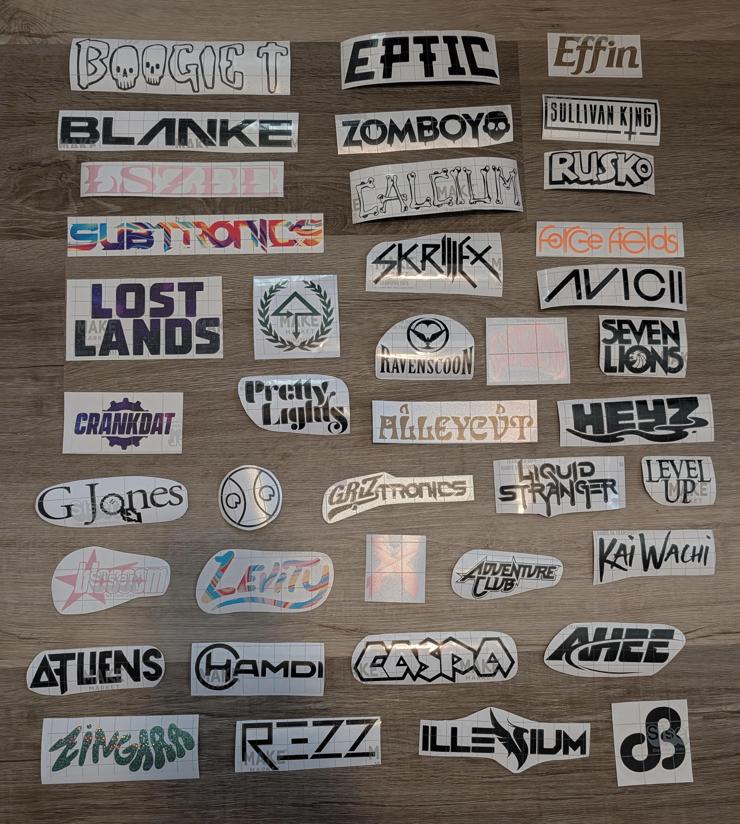 Collection of various cut-out stickers with different fonts, colors, and designs, arranged on a wooden surface.
